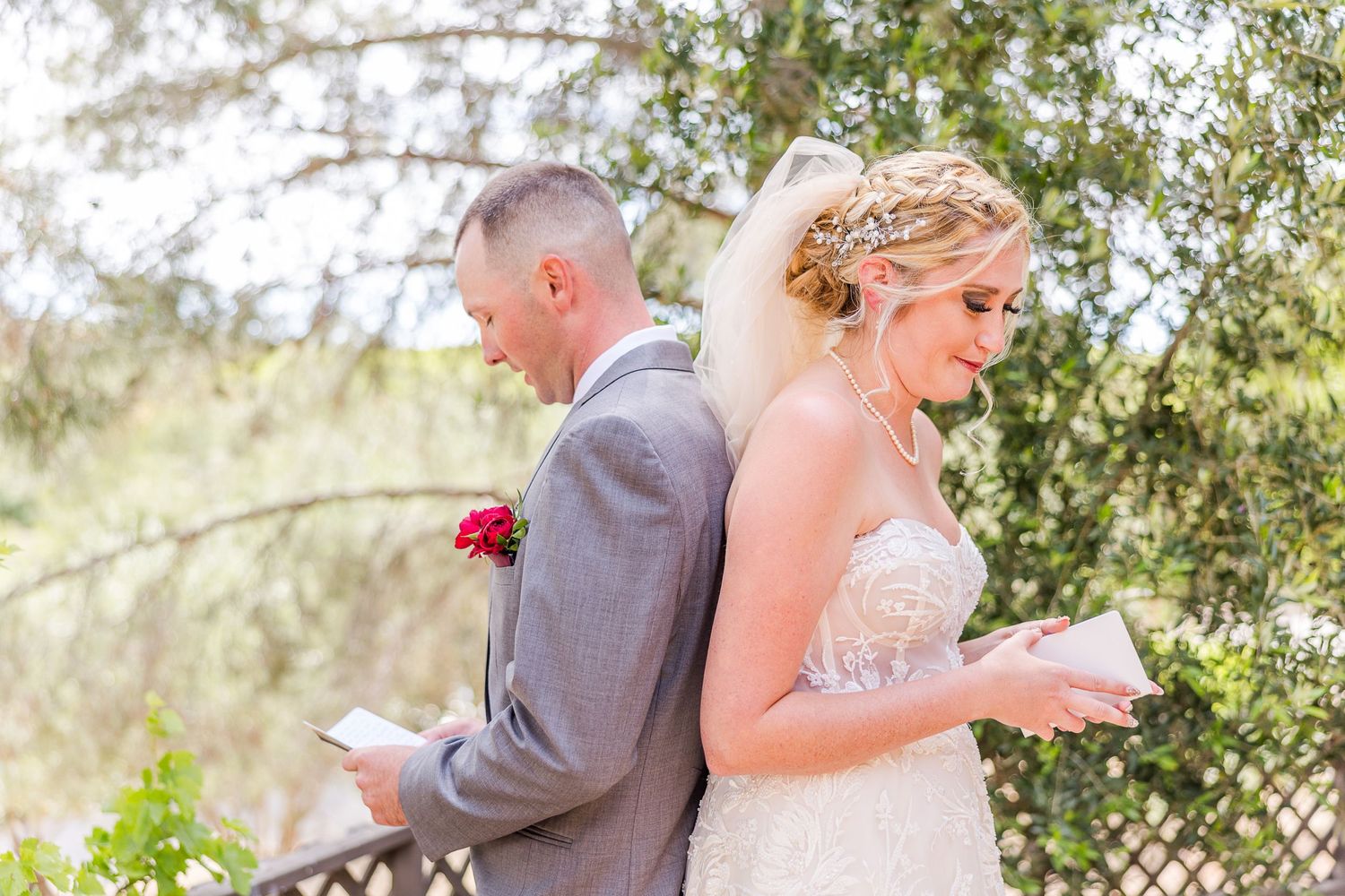 A couple shares a private first look moment reading letters before their wedding ceremony outdoors.