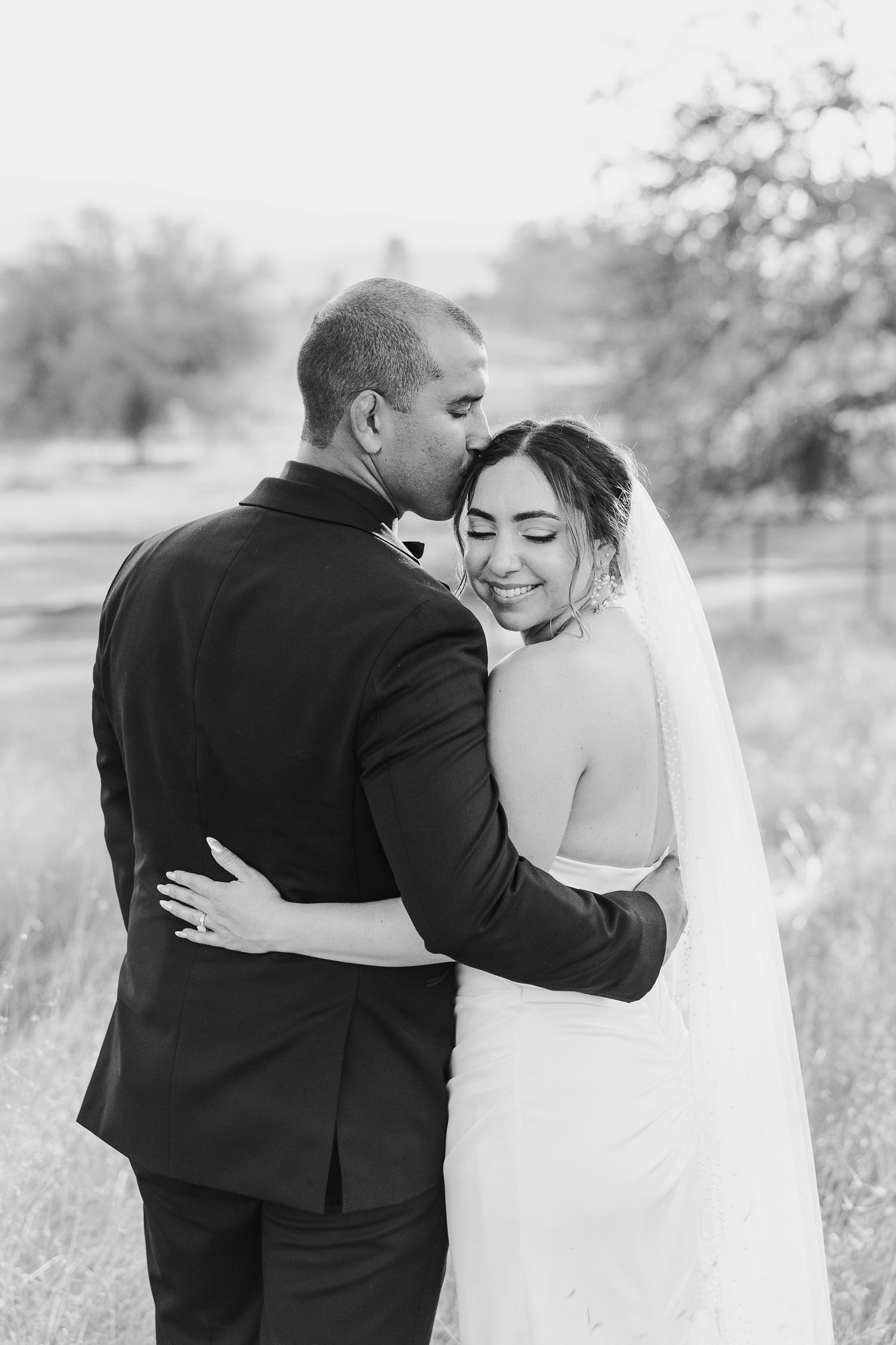 A romantic black and white wedding portrait series showing tender moments between a couple in an outdoor setting.
