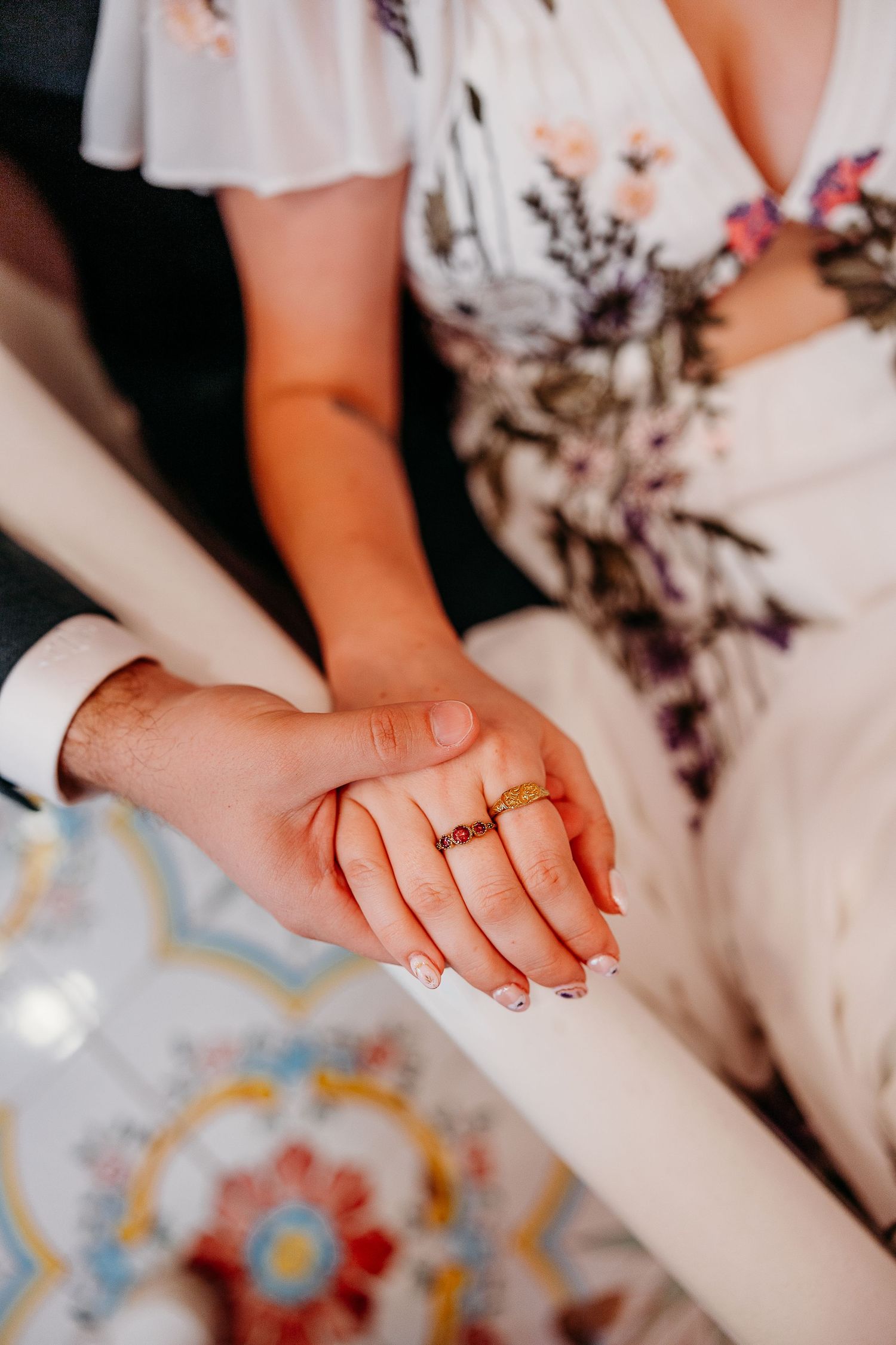 Close-up of hands holding each other with wedding rings during a romantic ceremony moment.