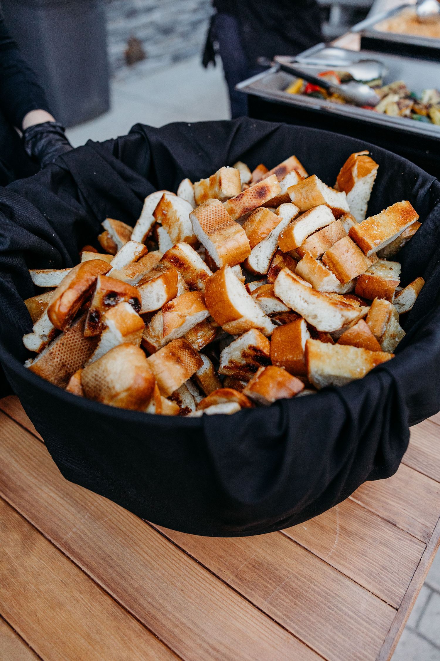 Basket of fresh bread pieces displayed at catering event.