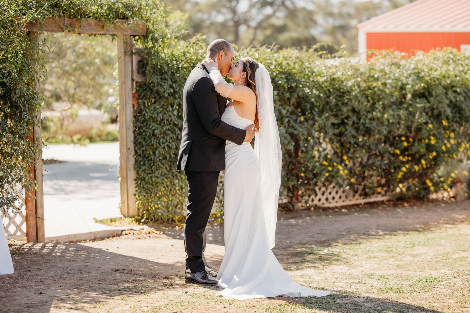 Wedding couple embracing under a floral arch during an outdoor ceremony.