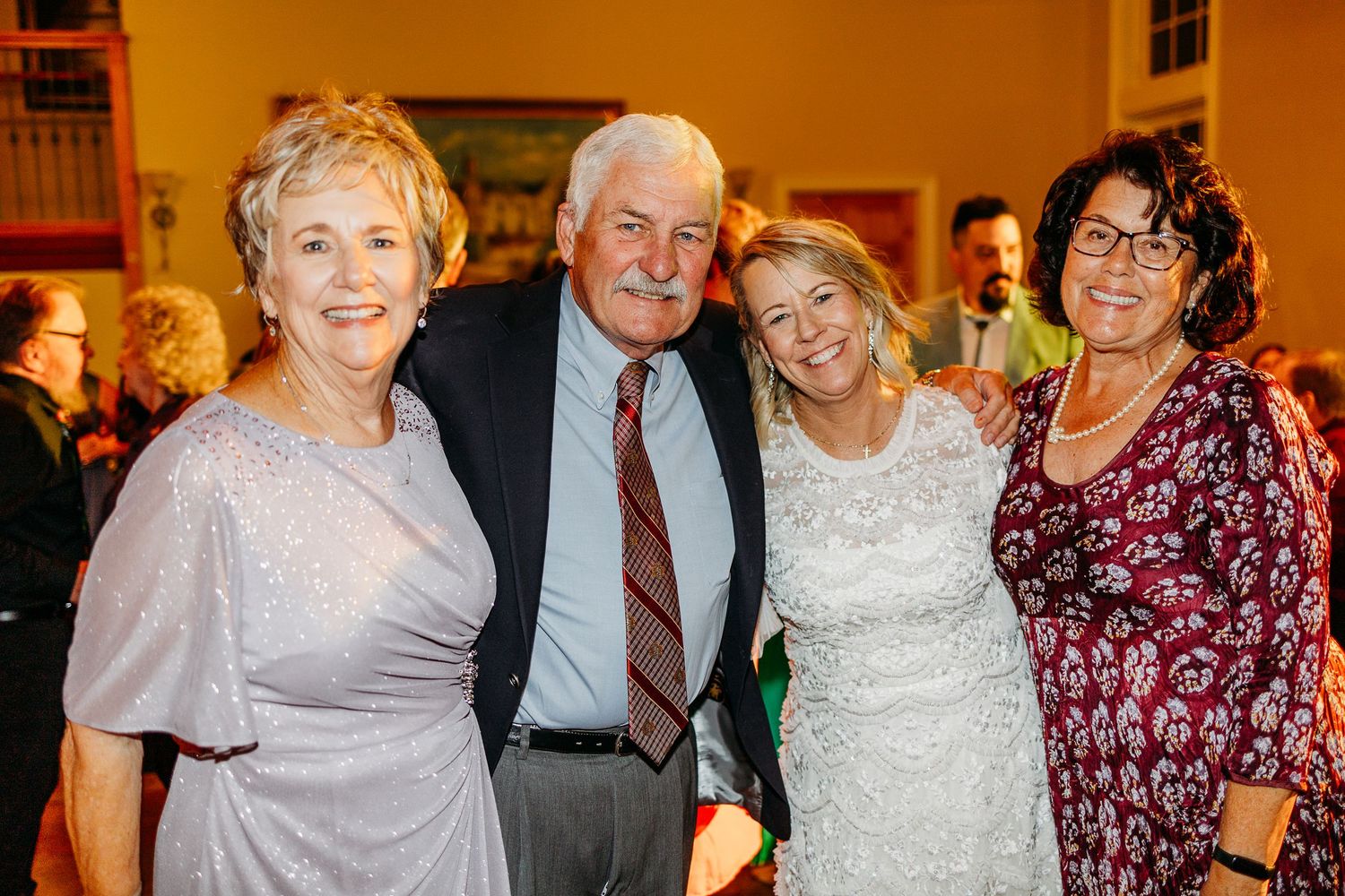 Wedding reception celebration with guests mingling in warm ambient lighting.