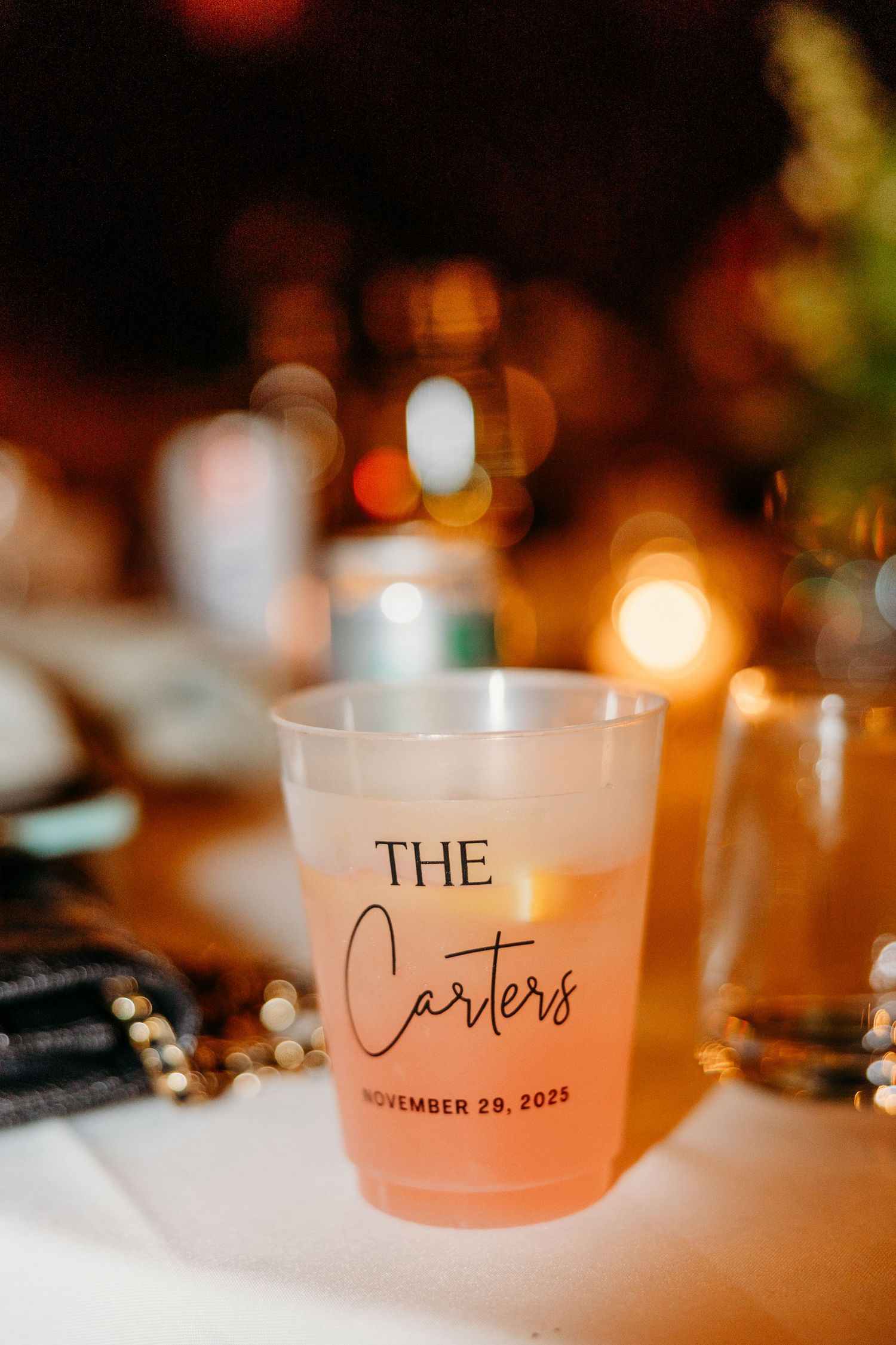 Wedding reception table features personalized frosted drink glasses with date and names.
