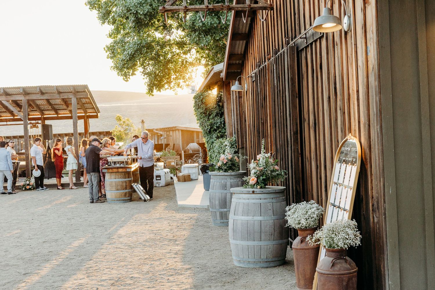 Rustic wooden barn wedding venue decorated with string lights and floral arrangements at dusk.