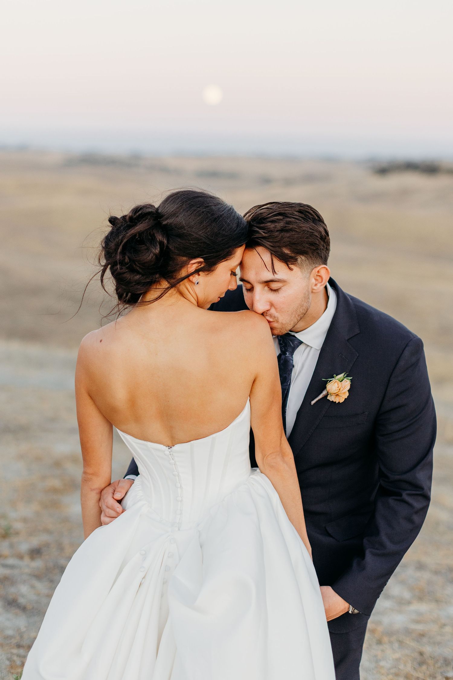 Intimate wedding portrait captured against a desert landscape at dusk.