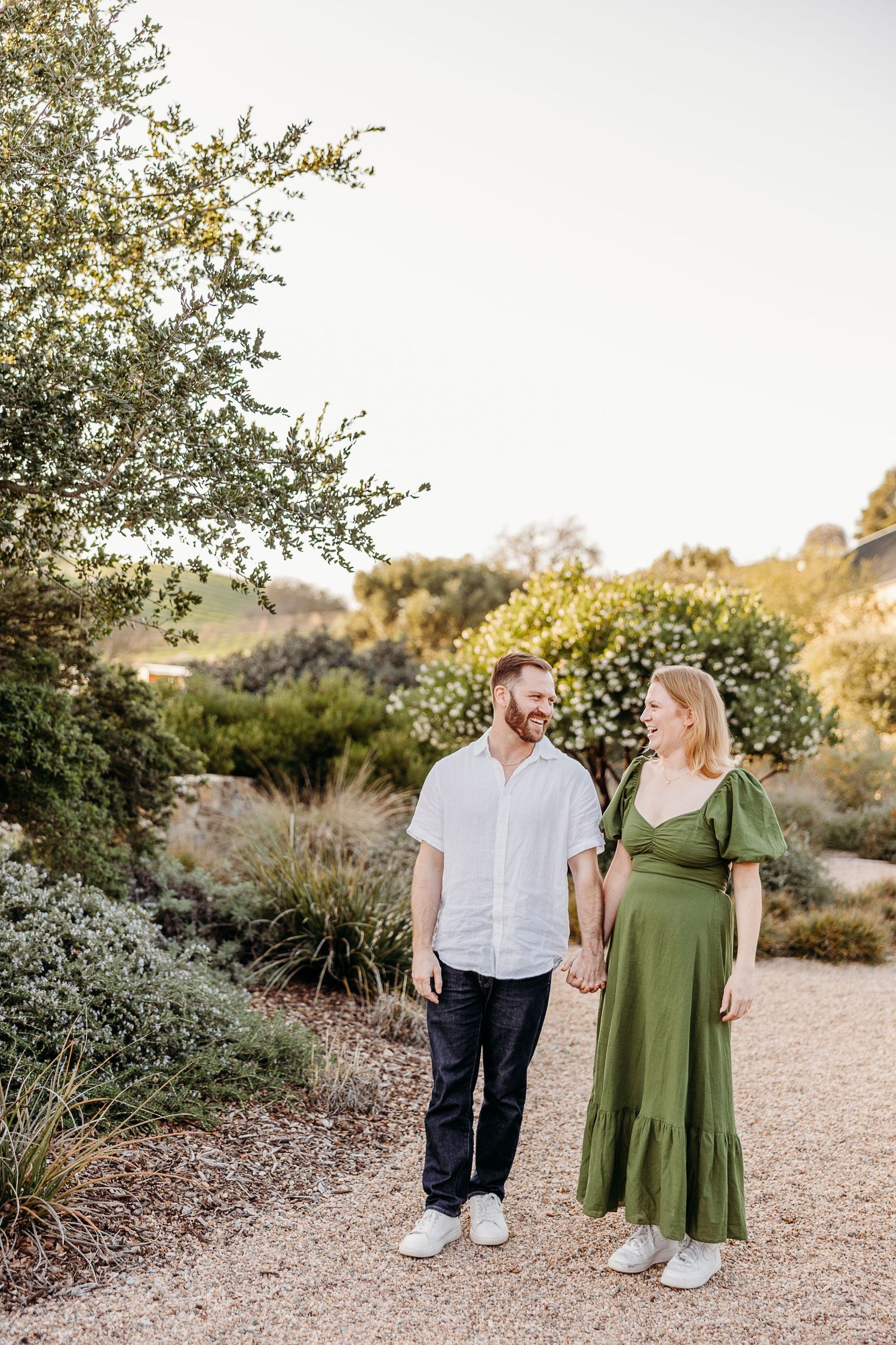 A couple walking together on a garden path surrounded by lush greenery and natural landscaping.