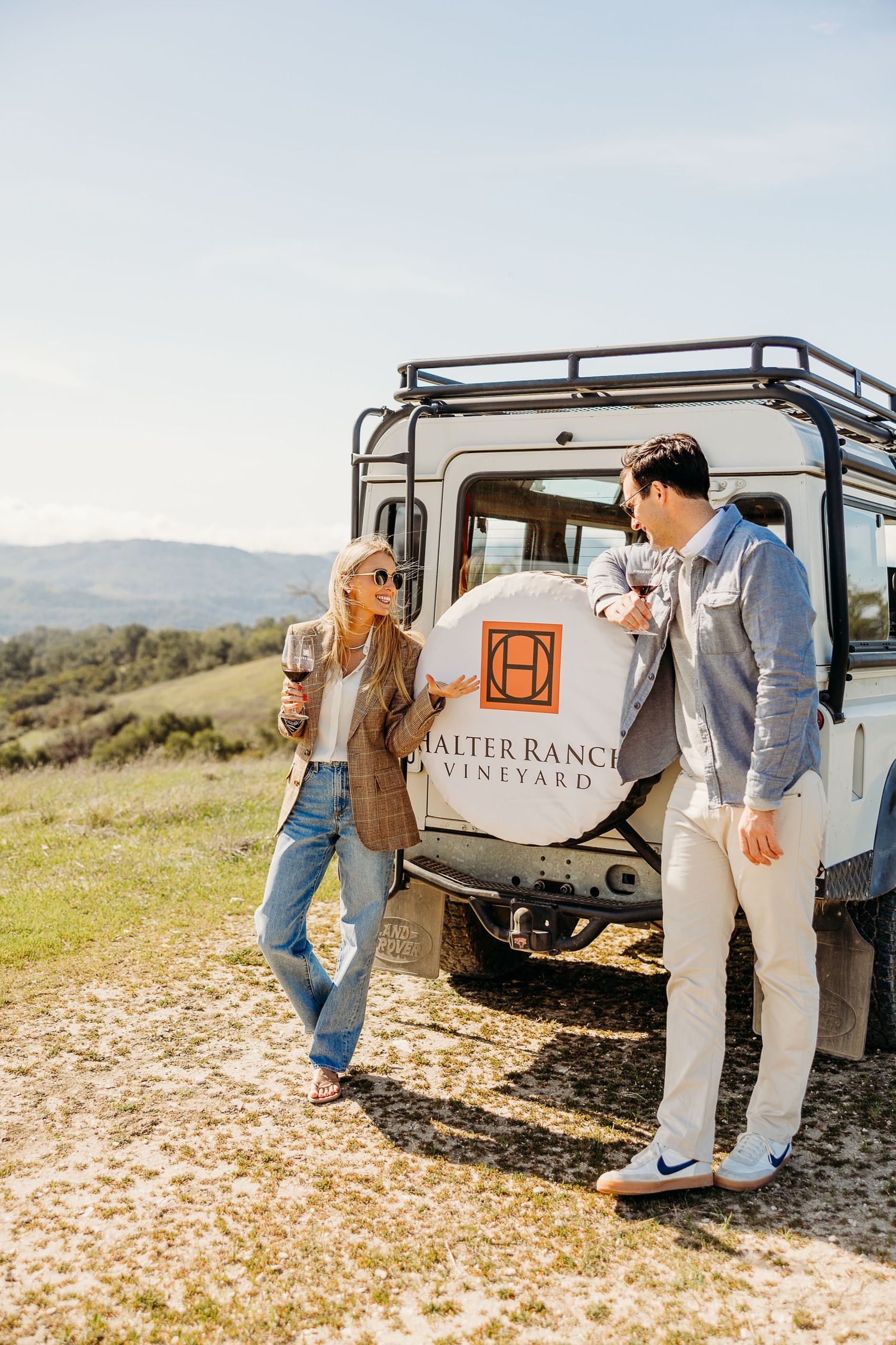 A vintage Land Rover vehicle parked in a scenic field during a special outdoor occasion.