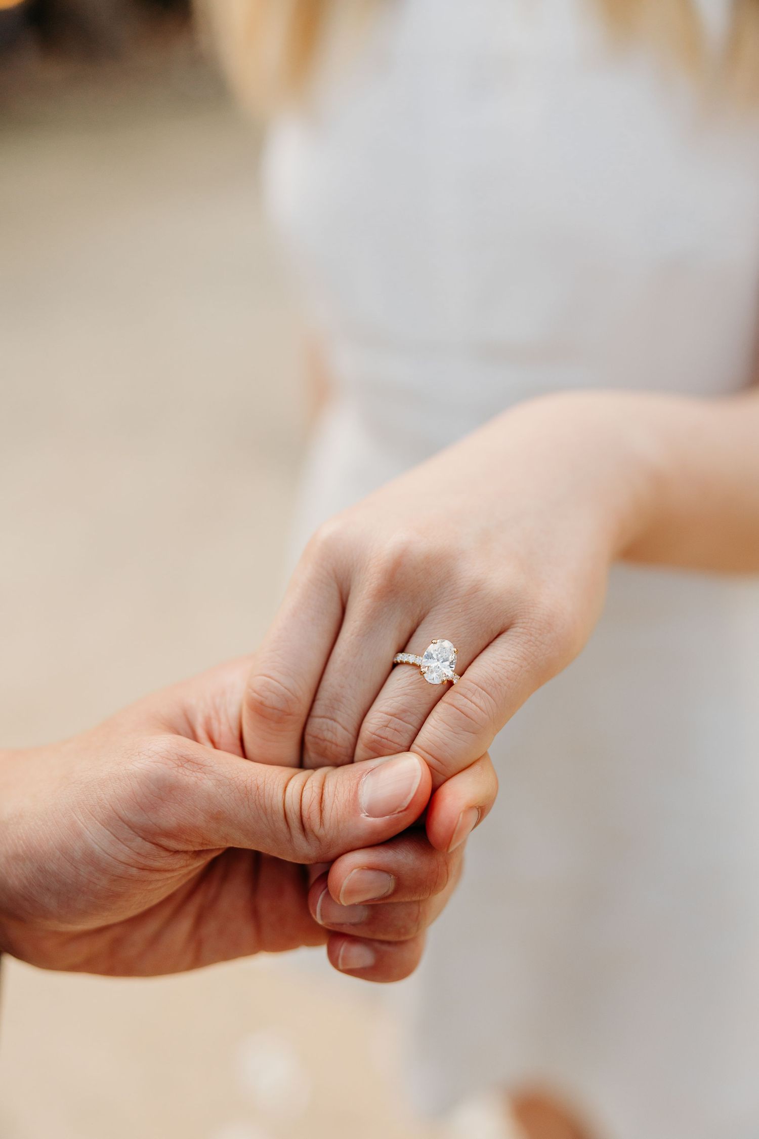 Close-up shots of hands showing off a sparkling engagement ring in natural light.
