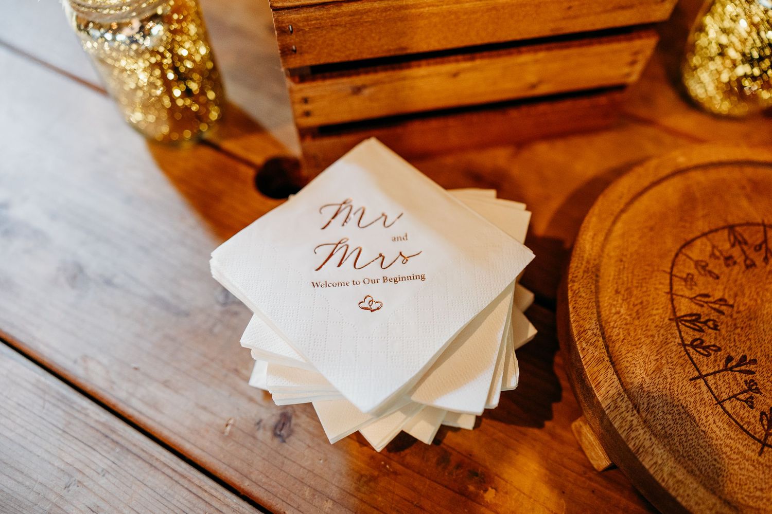 Elegant wedding stationery and decor details arranged on rustic wooden surfaces with gold accents.