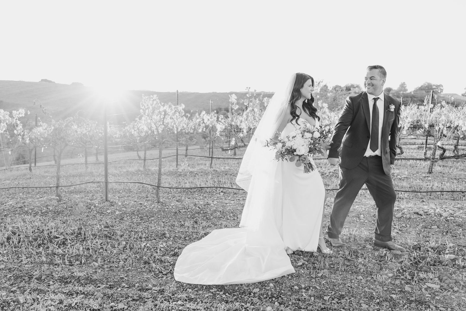 Black and white wedding photography capturing romantic moments in an outdoor vineyard setting.