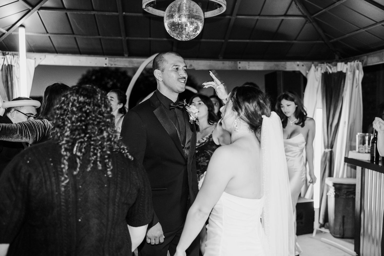 Black and white photo of a wedding reception dance party with disco ball overhead.