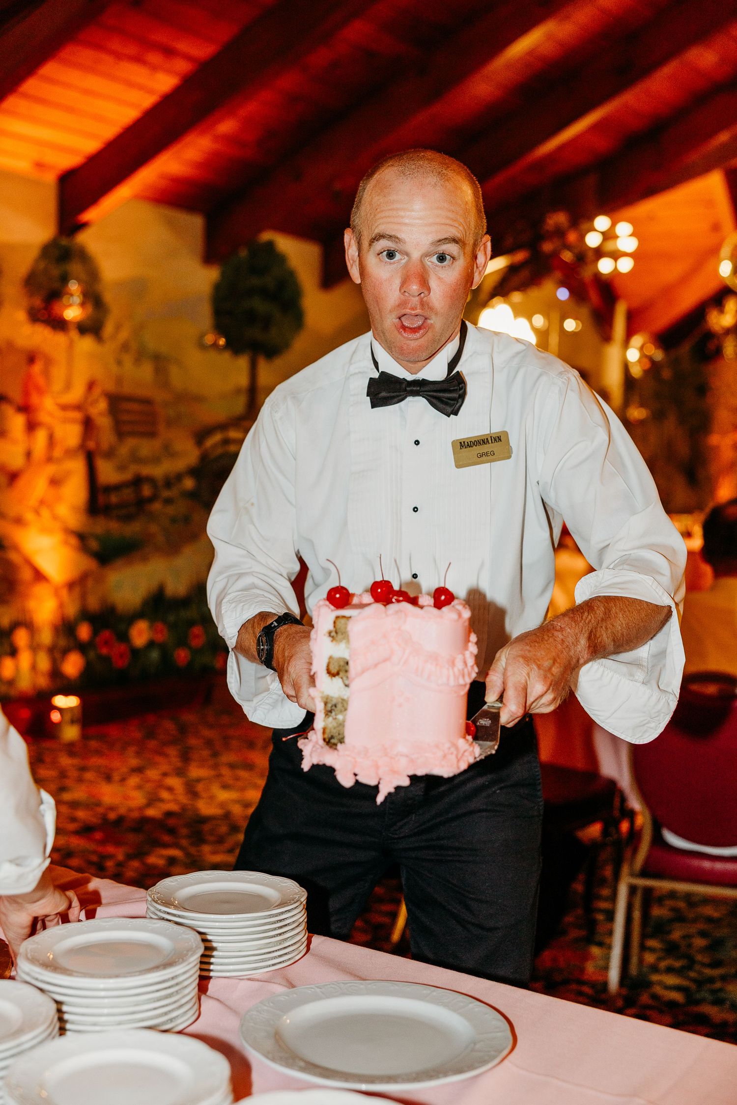 Waitstaff in formal attire serve pink desserts at an elegant wedding reception.