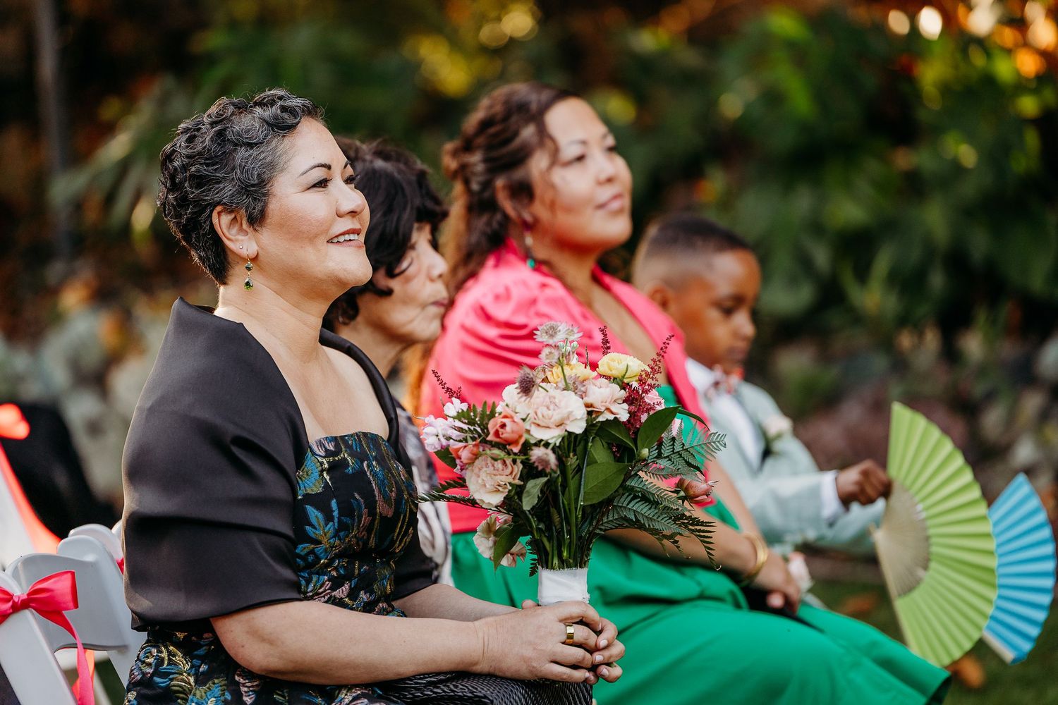 Wedding guests enjoying outdoor reception festivities with decorative hand fans.