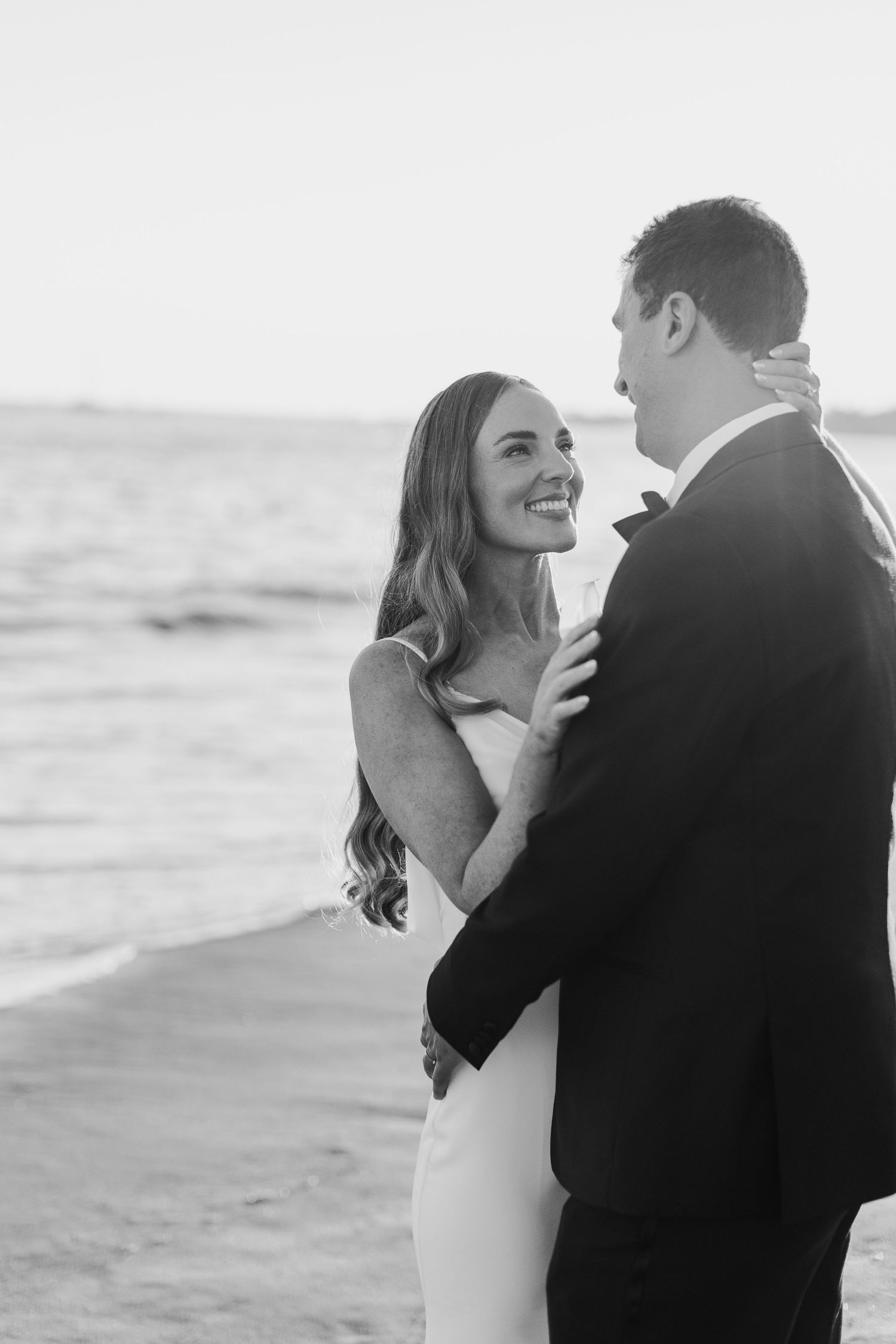 Black and white romantic beach portraits of a couple sharing intimate moments by the ocean.