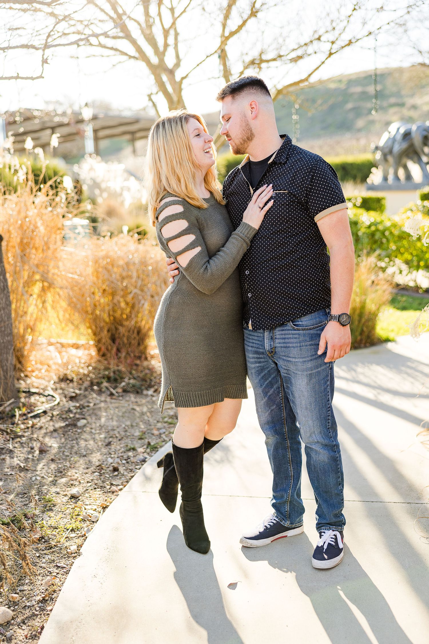 A couple shares an intimate moment on a garden pathway surrounded by winter foliage.