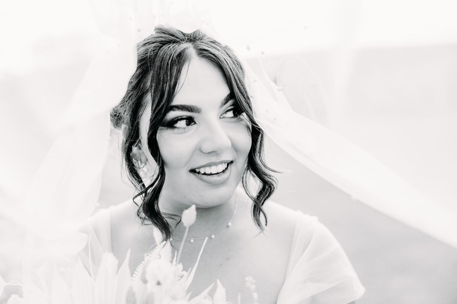 Black and white close-up portrait of bride with romantic curled hairstyle.
