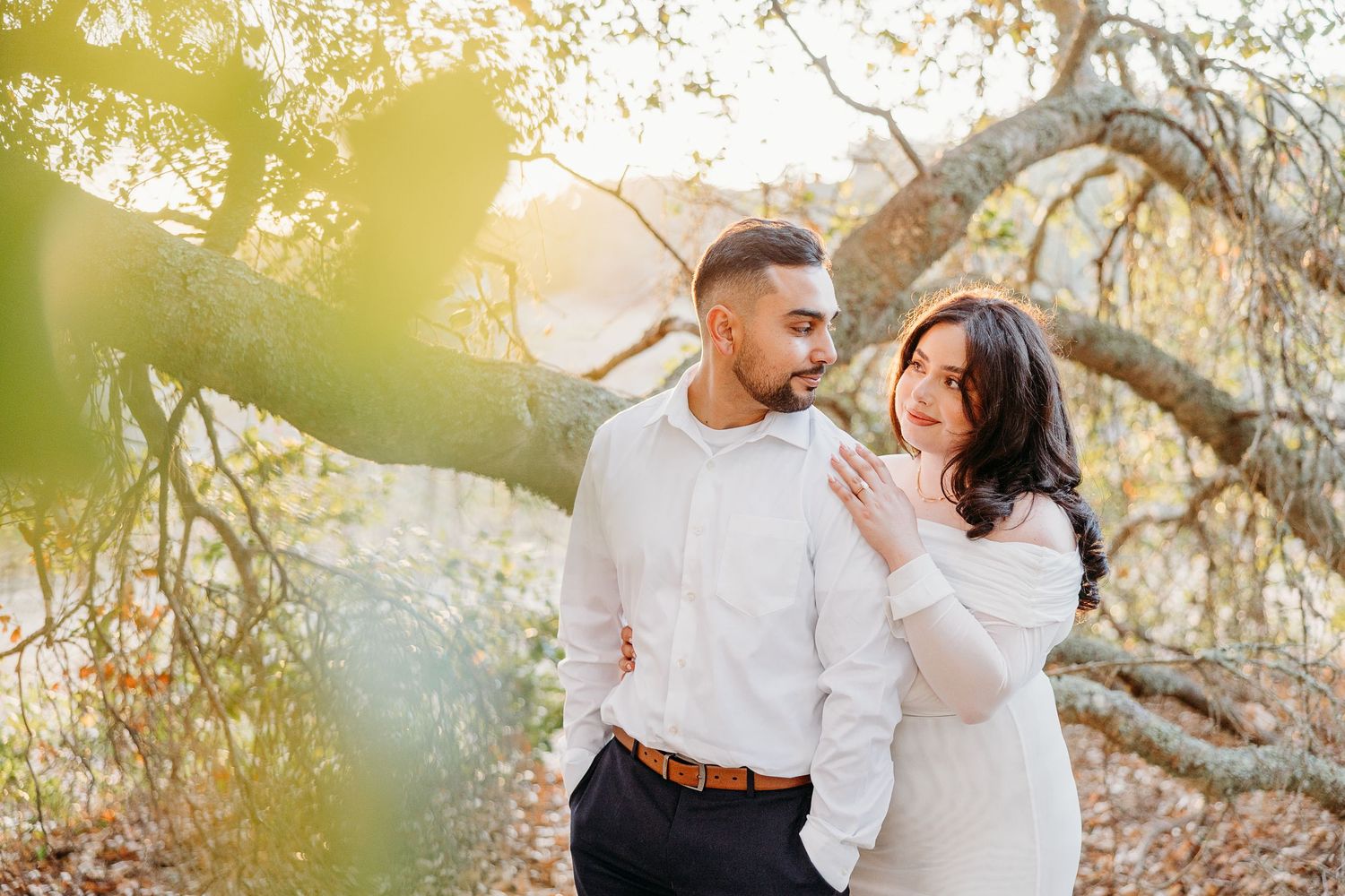Romantic sunset engagement photos with a couple posing under golden sunlit trees.