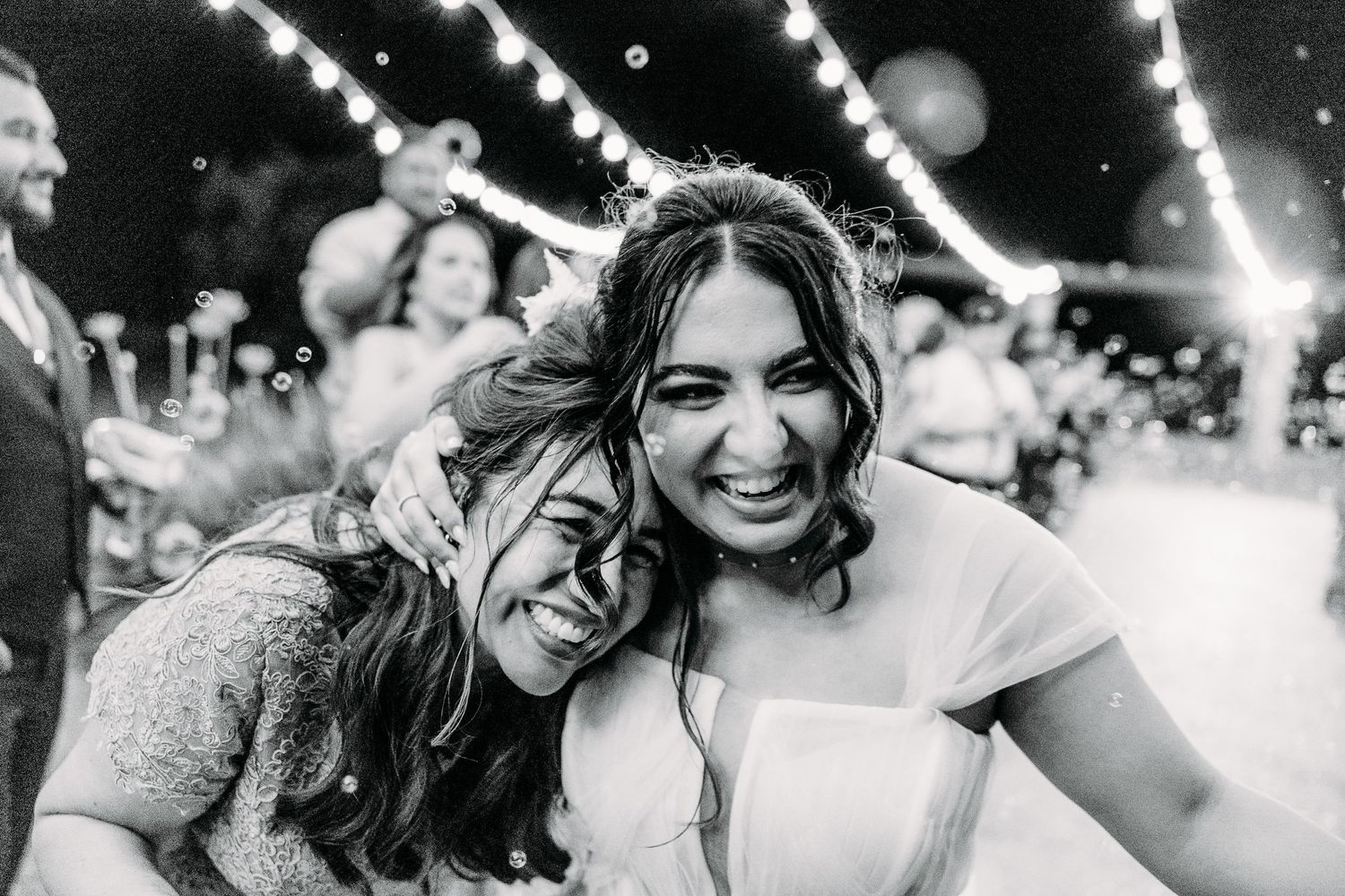 Black and white candid moment of joy captured during wedding celebration.