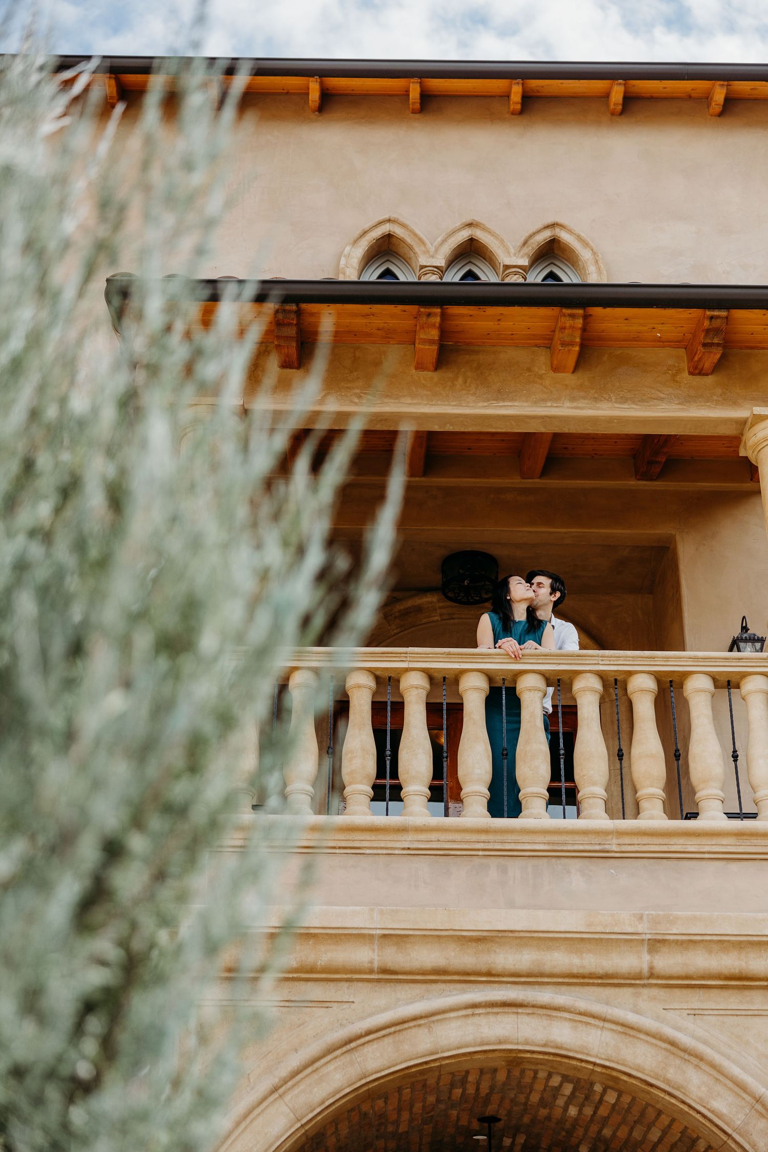 A scenic balcony view of an adobe-style building with arched architectural details and rustic wooden beams.