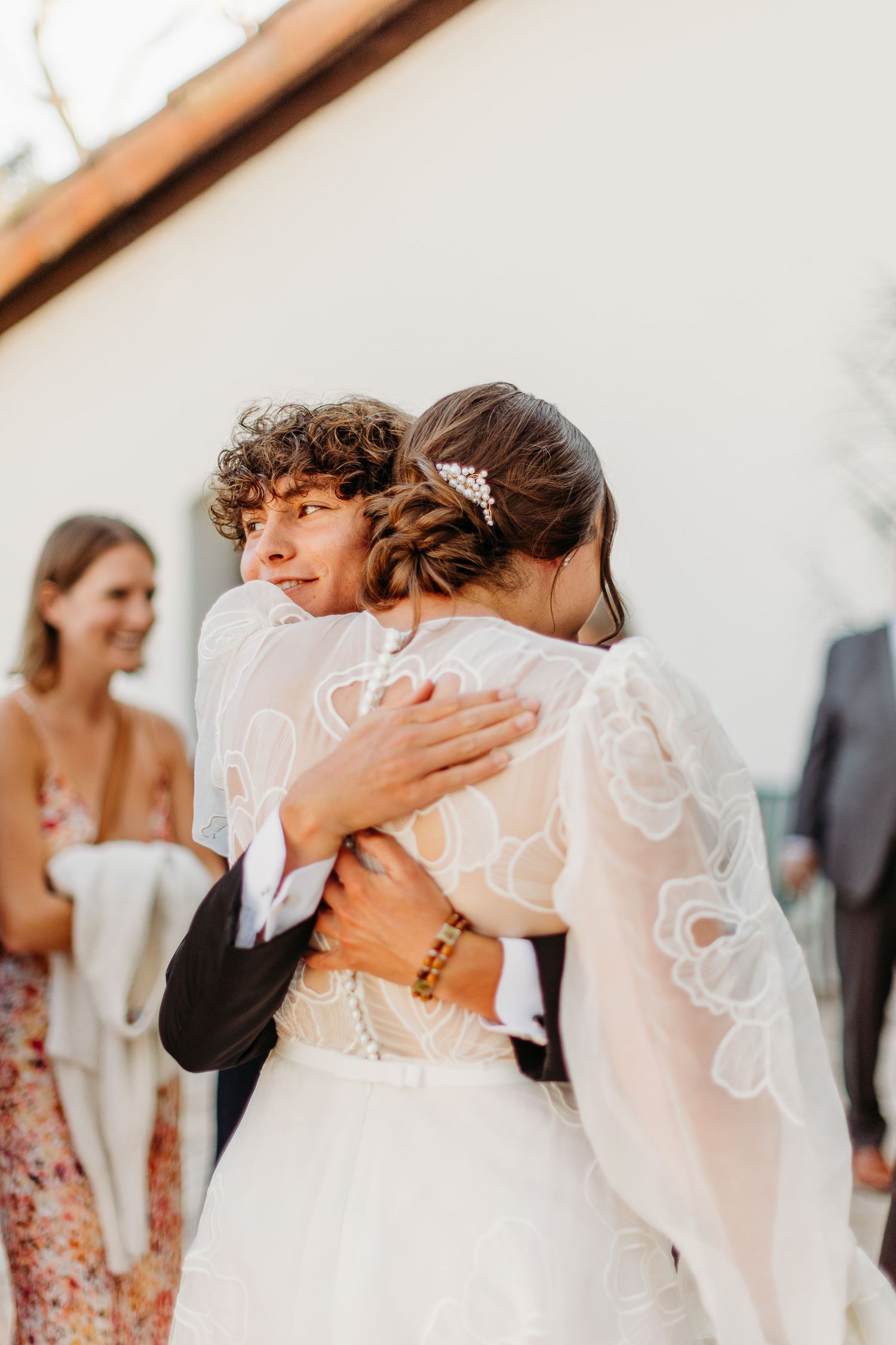 Tender embrace between couple in formal wedding attire during outdoor celebration at Mission San Luis Obispo.