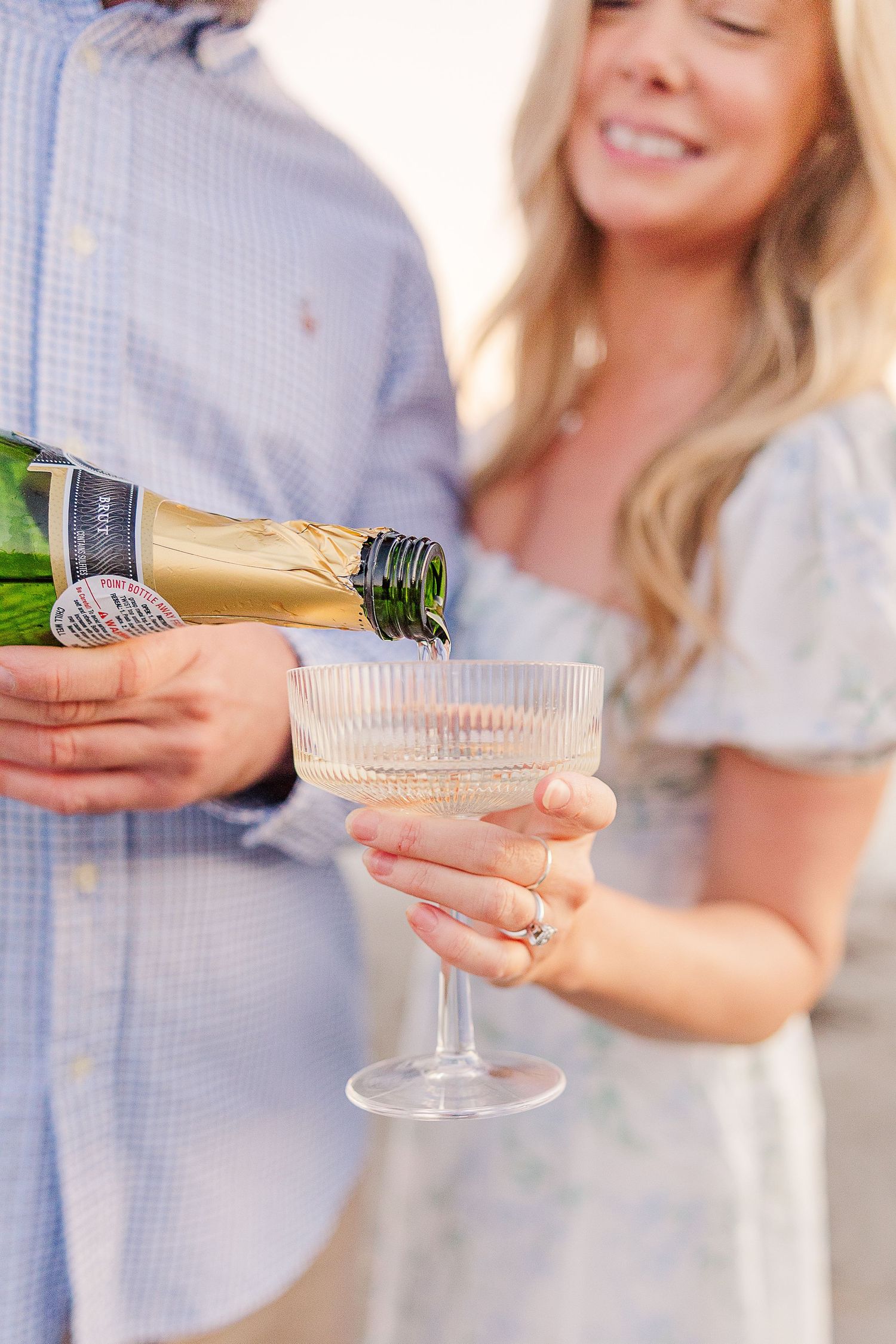 Hands pouring champagne into vintage crystal coupes for a celebration.