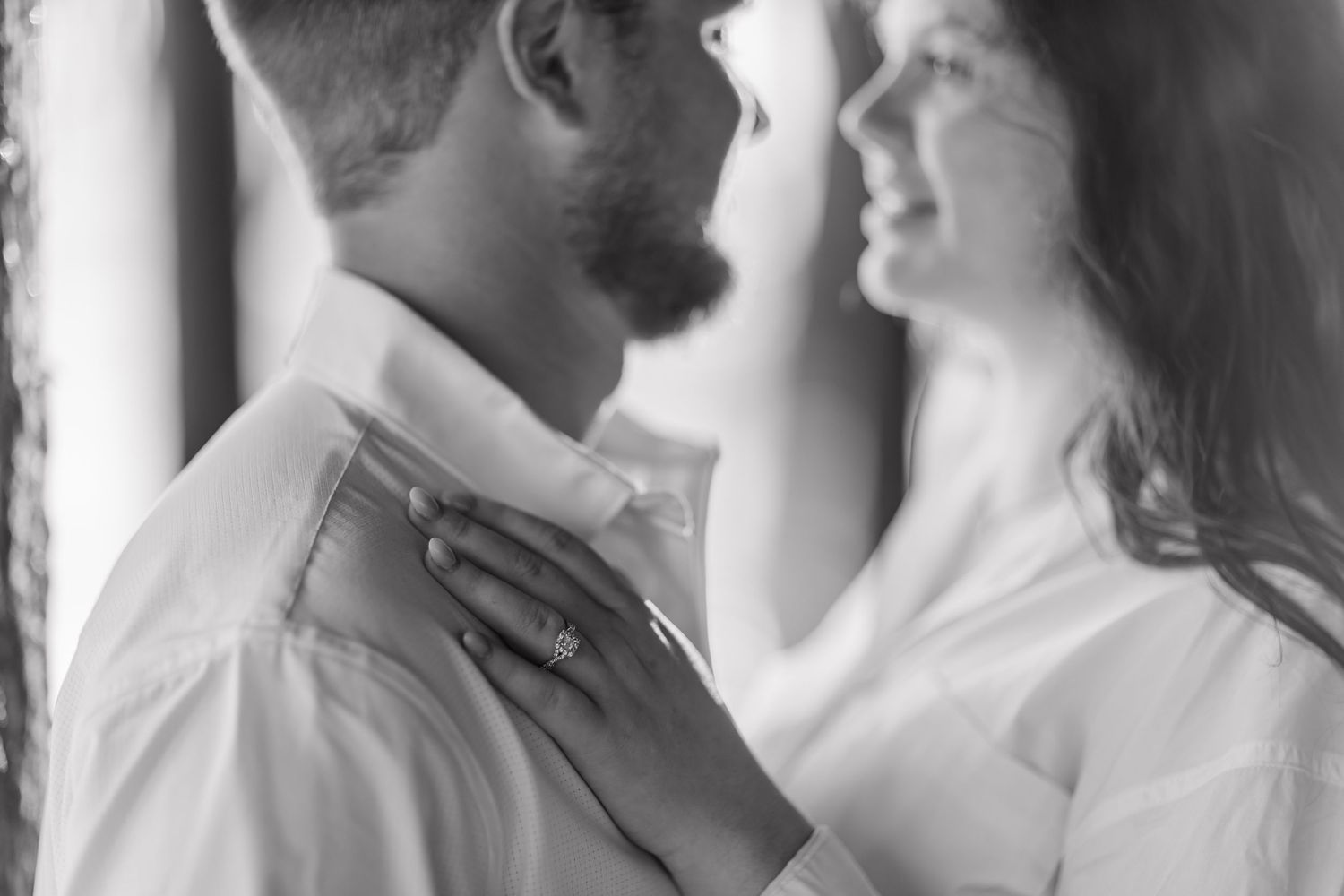 Intimate black and white portrait of couple in white shirts sharing a tender moment.