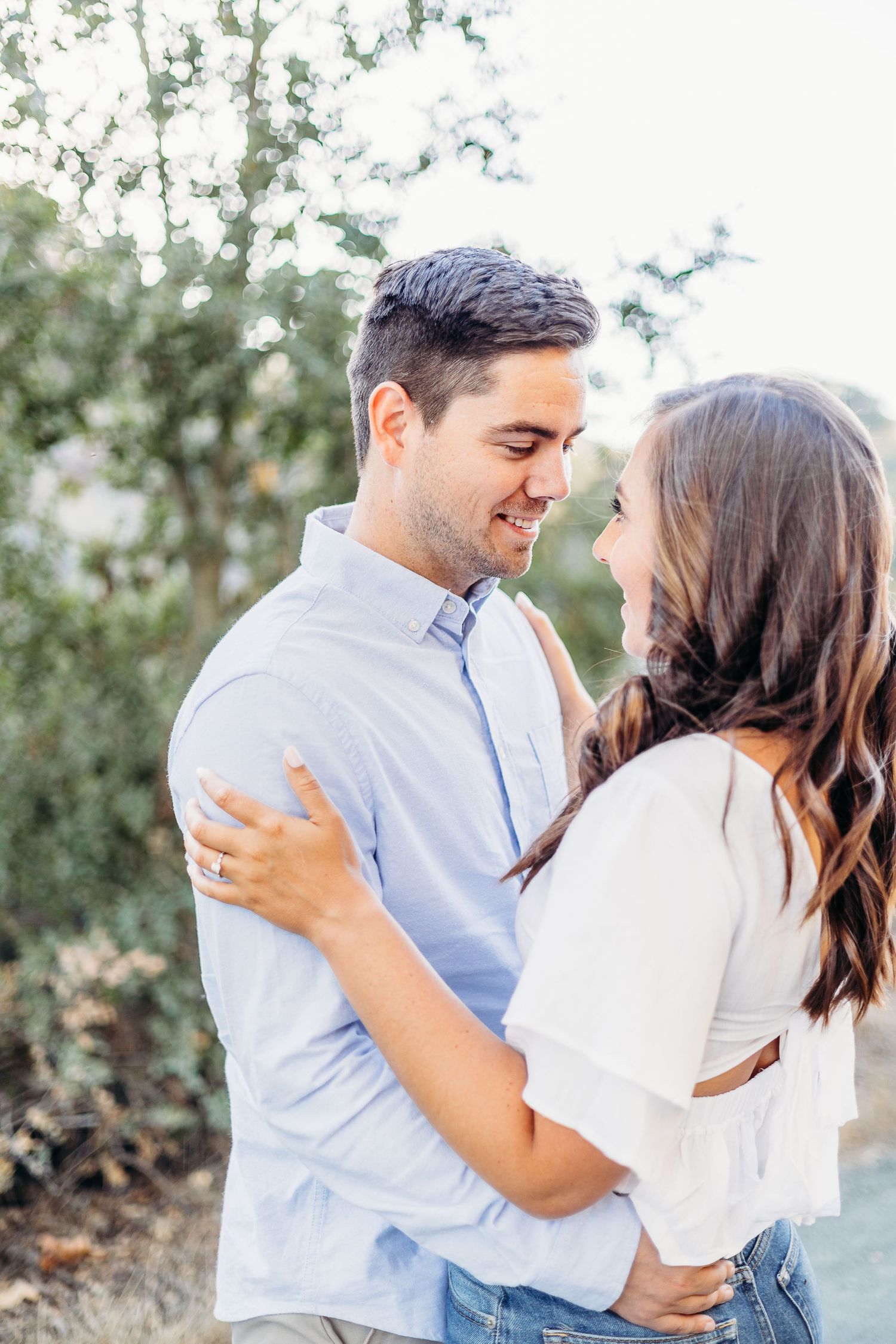 A couple sharing a tender moment while embracing on an outdoor path.