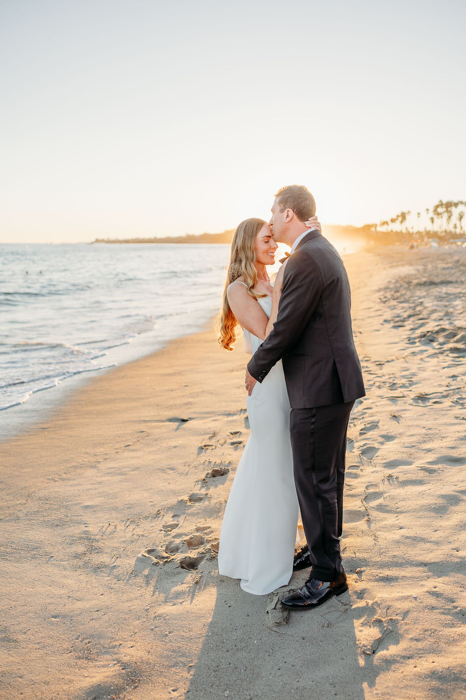 Romantic beach wedding photos during golden hour on sandy shore.