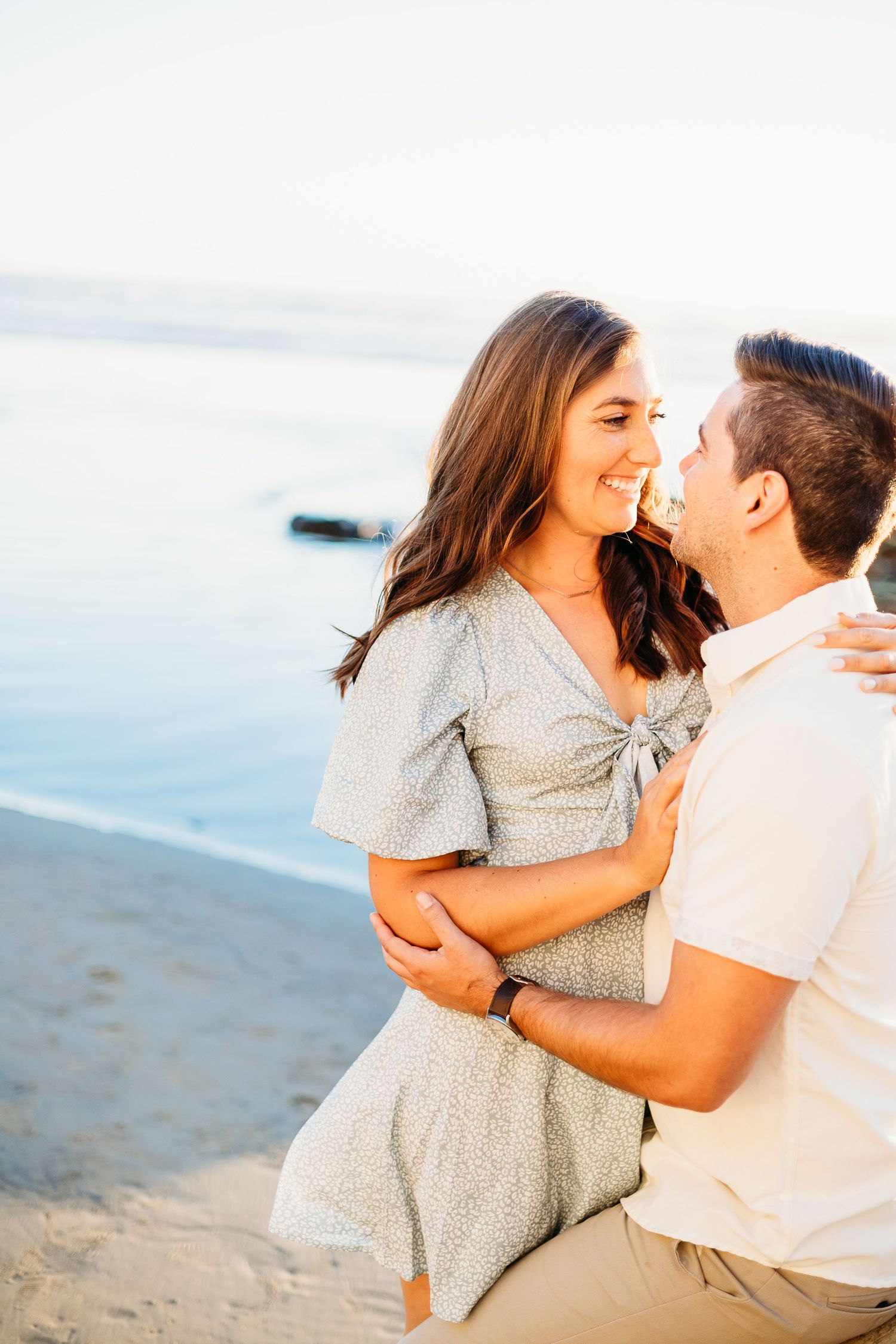 A couple shares an intimate moment while embracing on a beach at sunset.