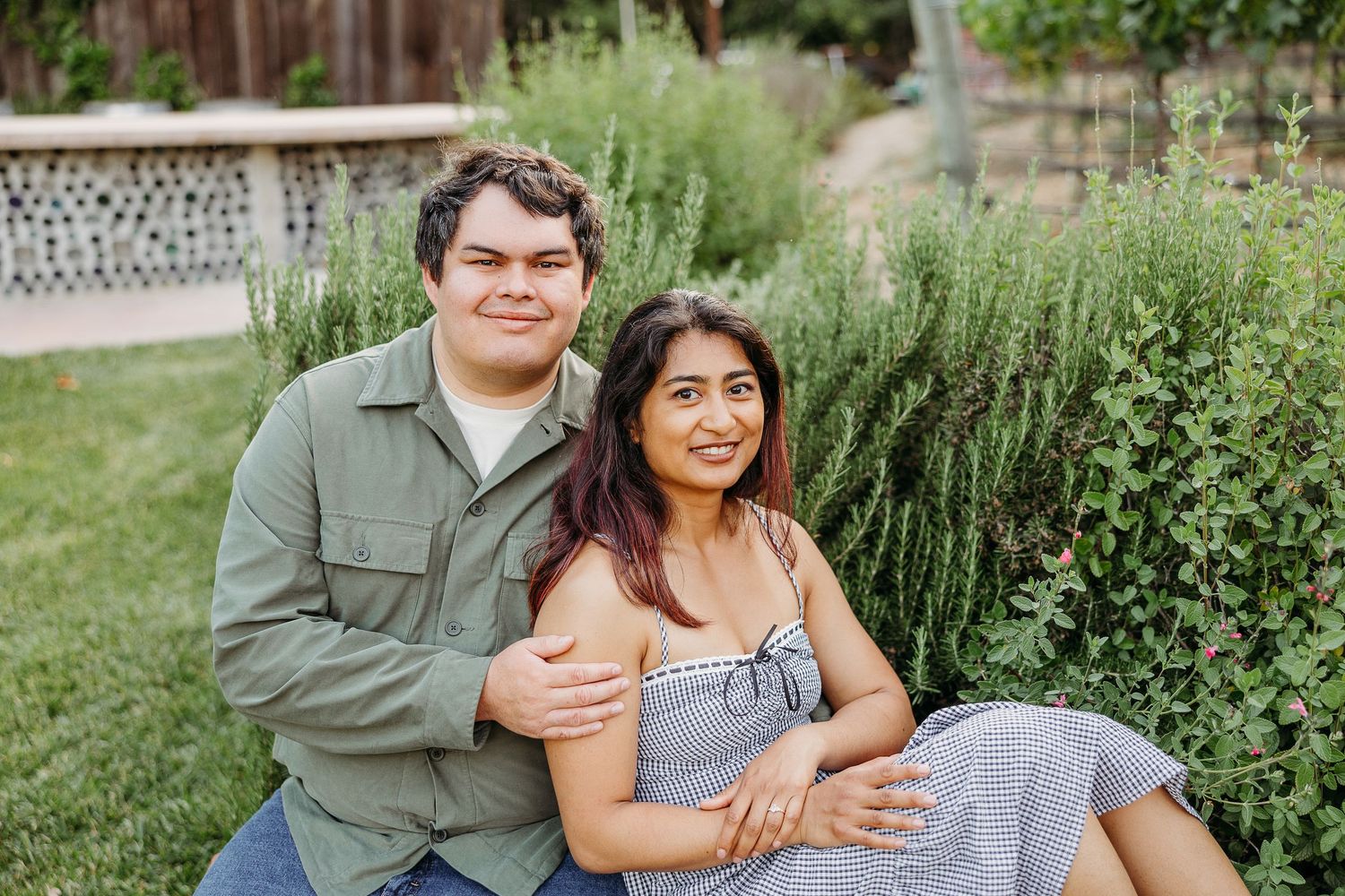 A couple embraces in multiple candid poses while standing in a lush garden setting during a photo session.