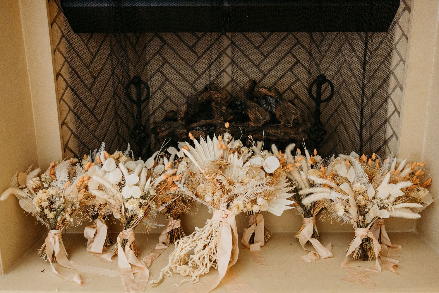 Beautiful dried floral wedding bouquets arranged in a decorative fireplace with herringbone tile pattern.