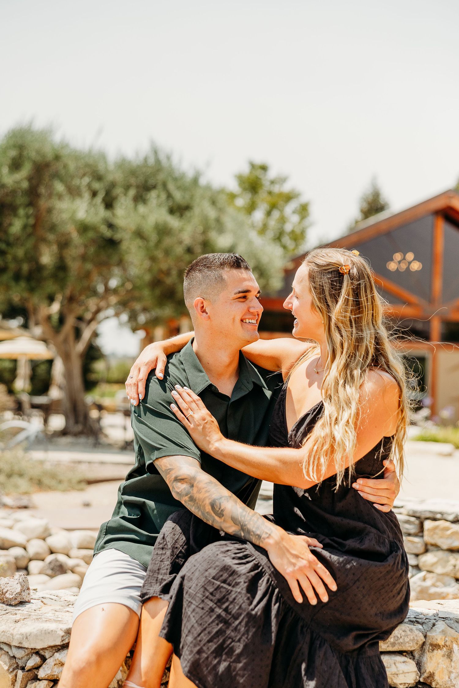 A couple sitting on stone steps share playful and affectionate moments together in a sunny outdoor setting.