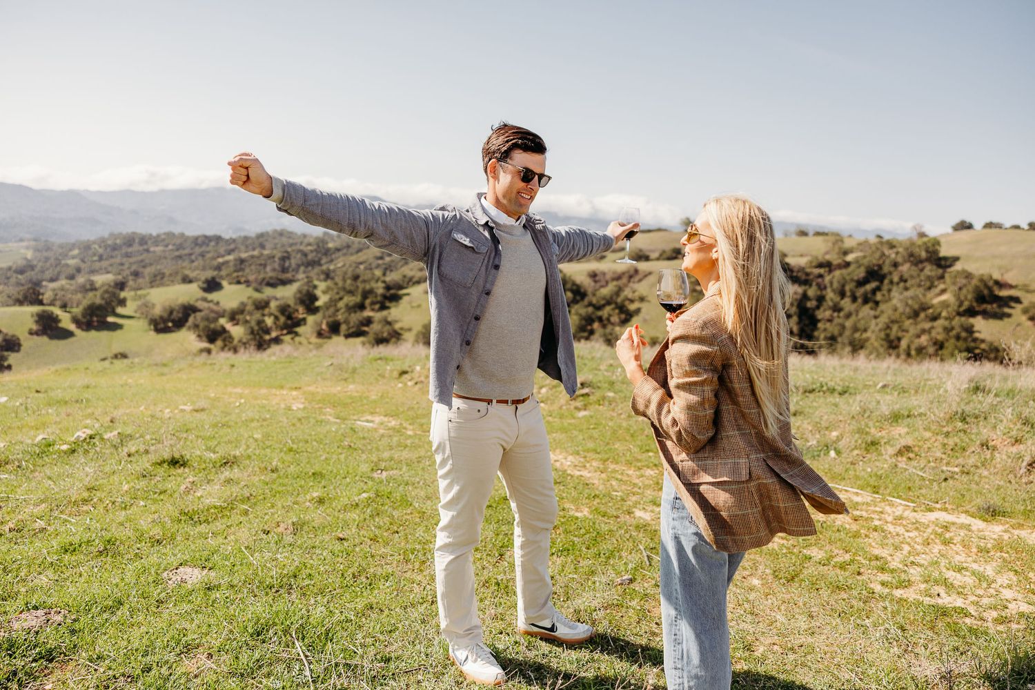 Couple sharing celebratory moment on scenic hilltop during golden hour.