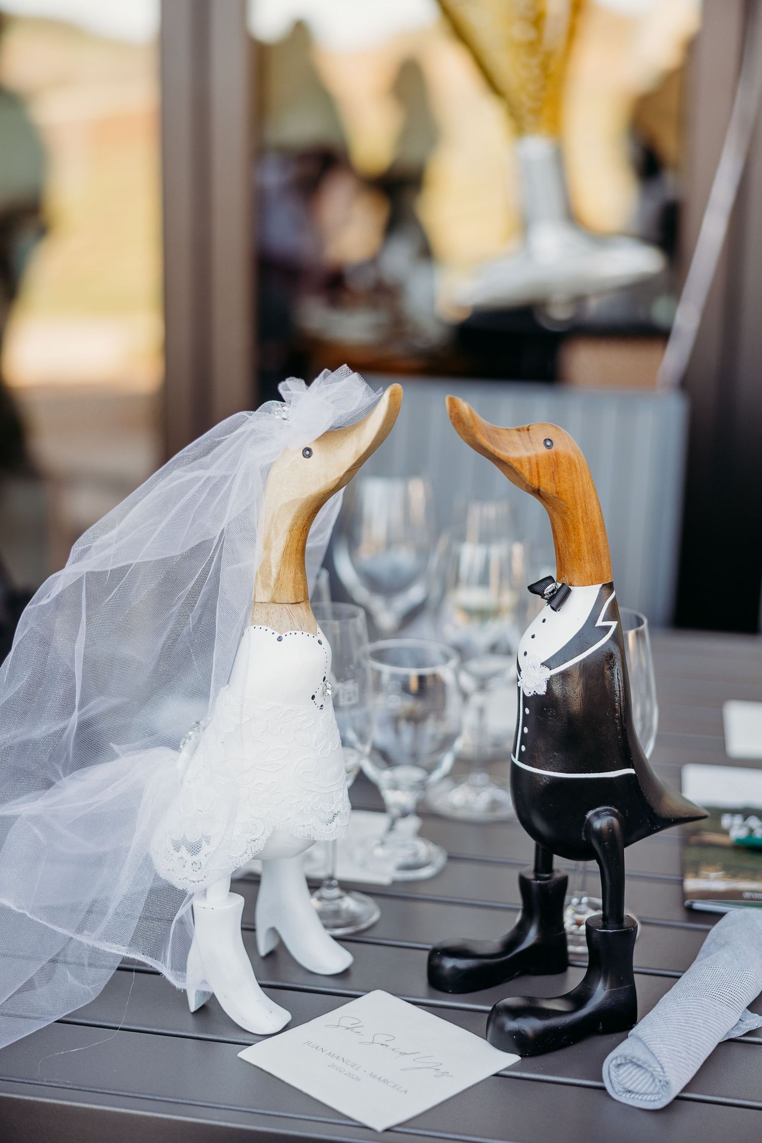 Wedding cake toppers featuring black and white penguin figurines with a bridal veil on display.