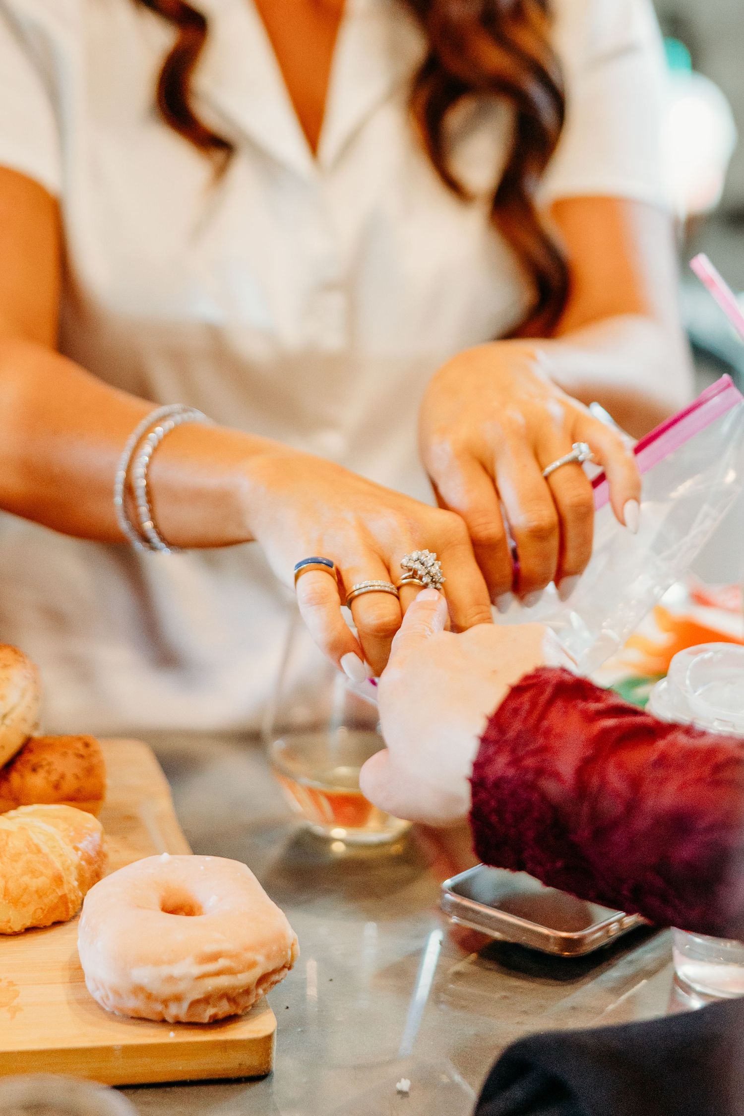 Close-up shots of hands with wedding rings selecting and eating colorful donuts.