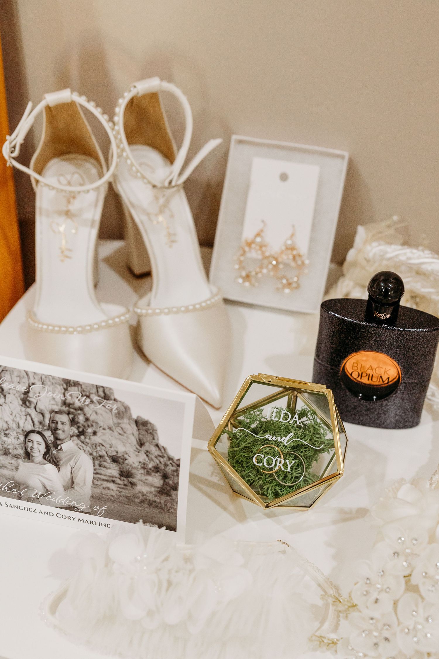 Wedding details including white shoes, rings, and vintage photographs arranged on a light surface.