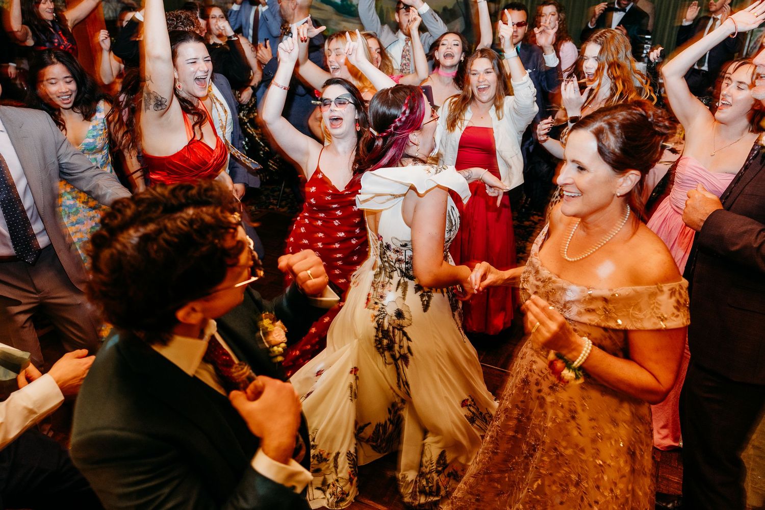 Wedding reception guests dancing and celebrating on a crowded dance floor.