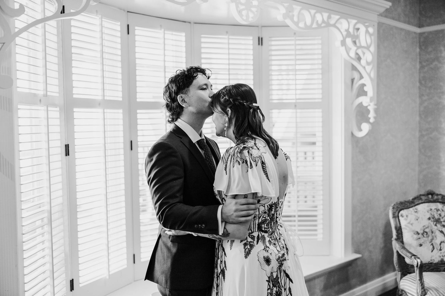 Black and white wedding photo collage showing intimate moments between couples in formal attire by sunlit windows.