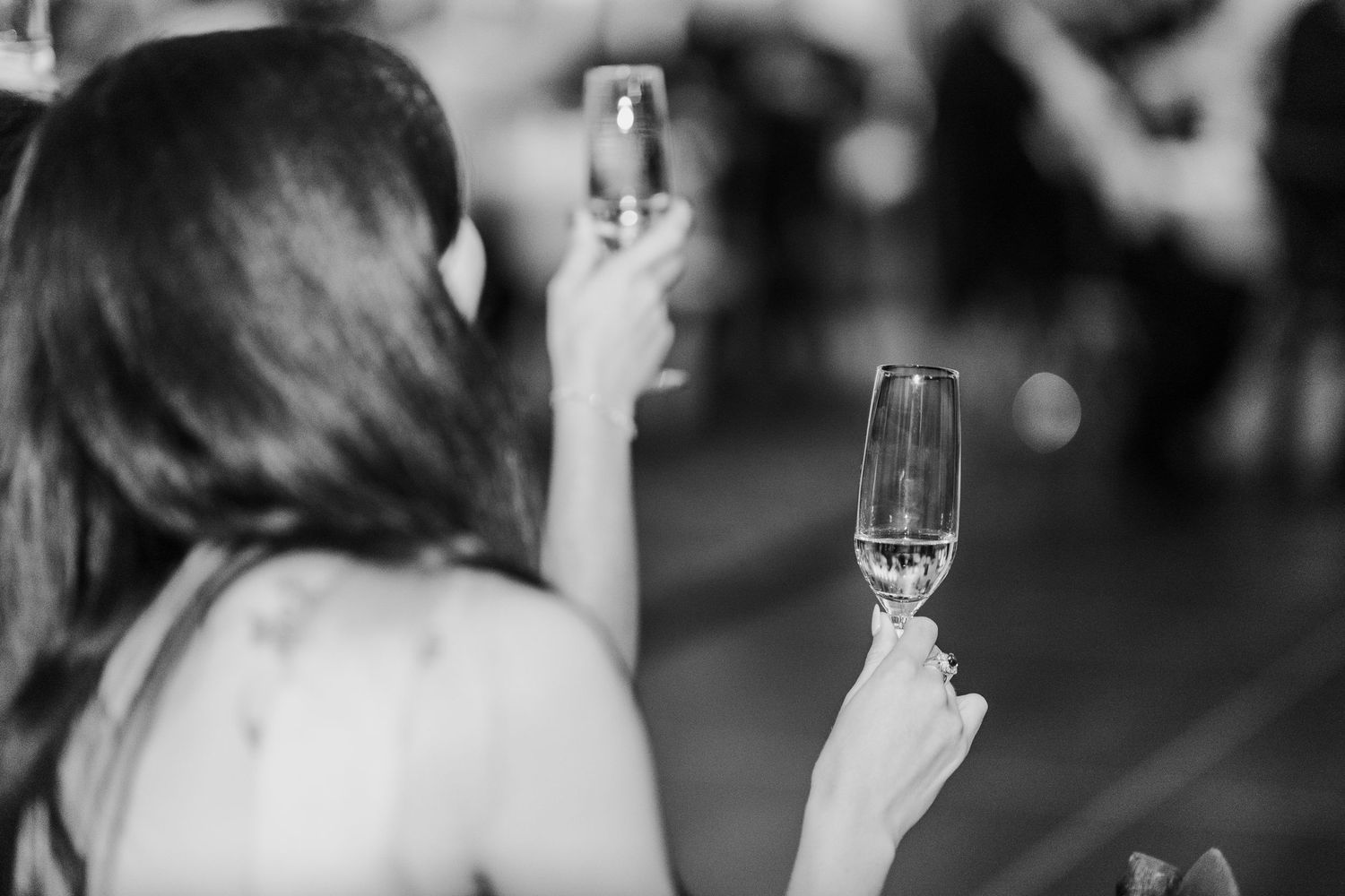 Black and white photos of wedding guests toasting during reception celebrations.