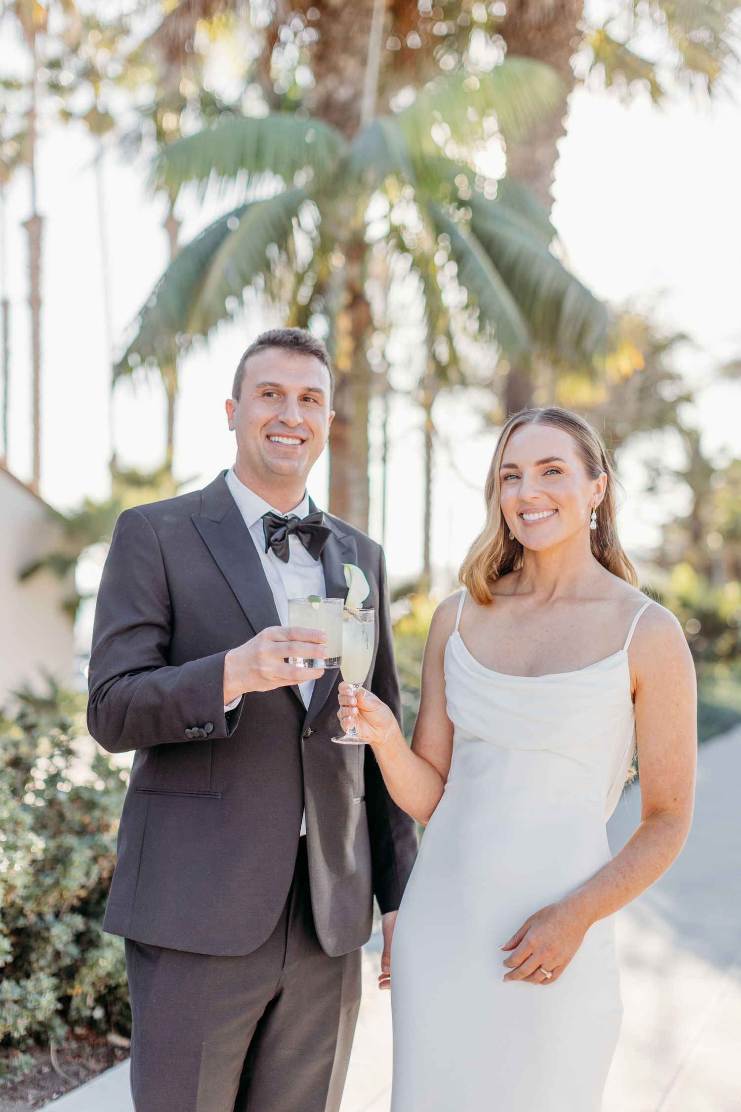 Wedding couple shares joyful moments and champagne toasts during outdoor sunset photo session.