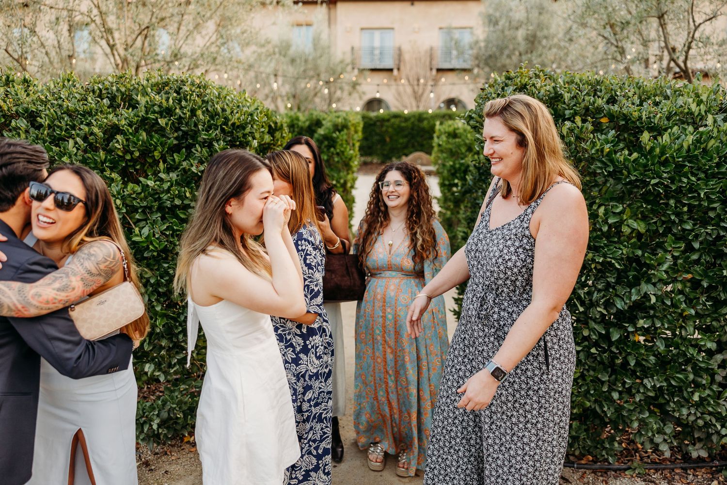 Friends sharing joyful moments outdoors against a backdrop of green hedges.