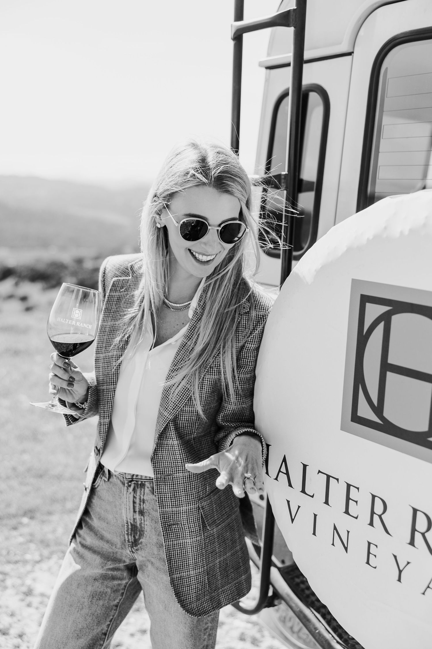 Woman enjoying wine while leaning against a vineyard tour vehicle.