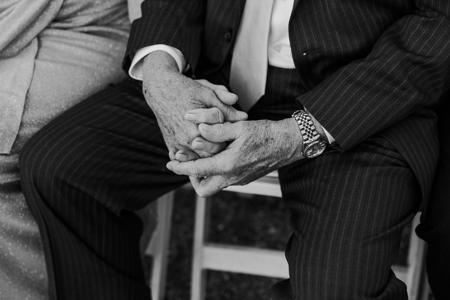 Black and white detail shot of hands during an emotional wedding ceremony moment.