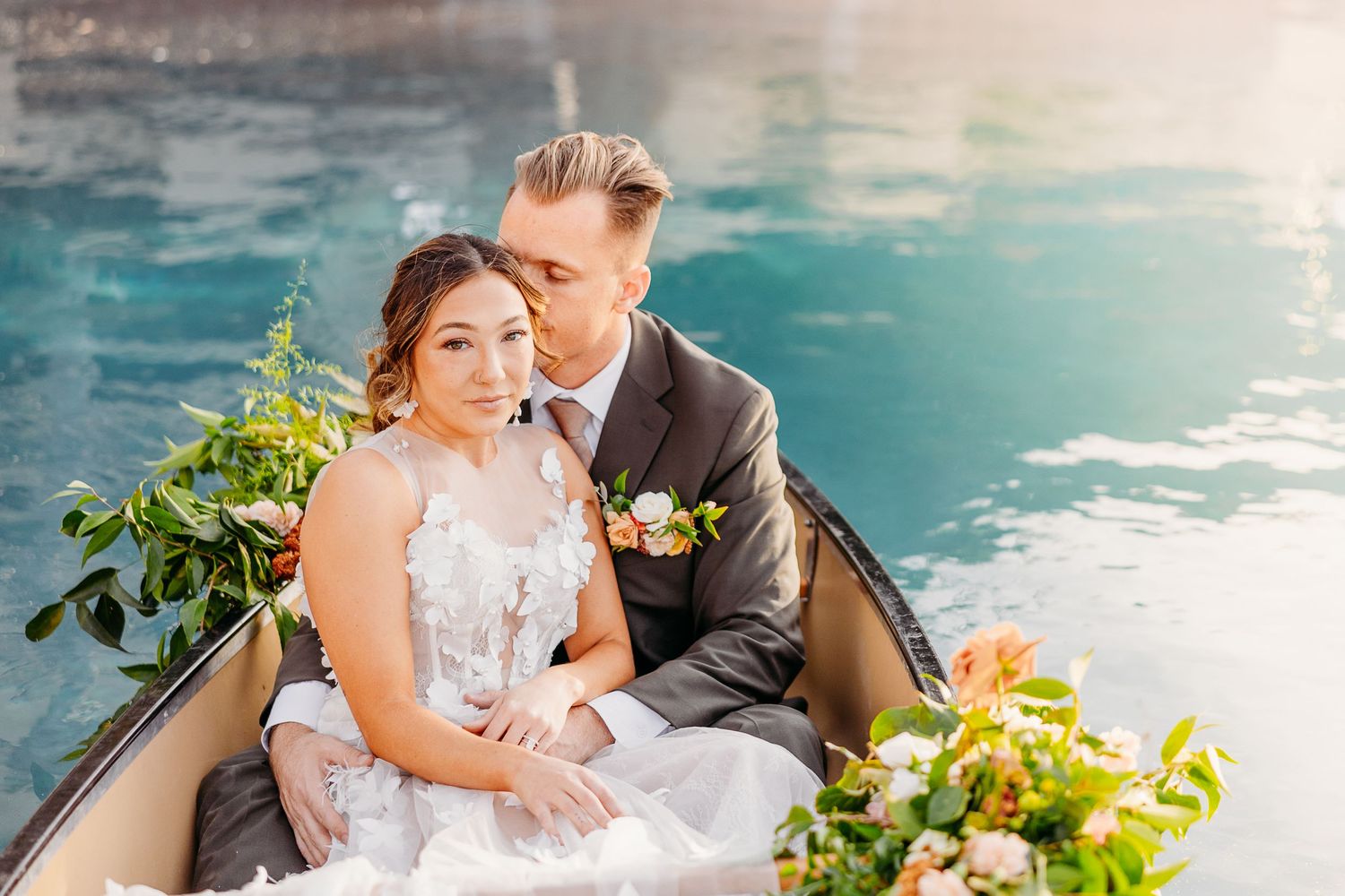Romantic wedding couple poses by a turquoise pool with floral arrangements.
