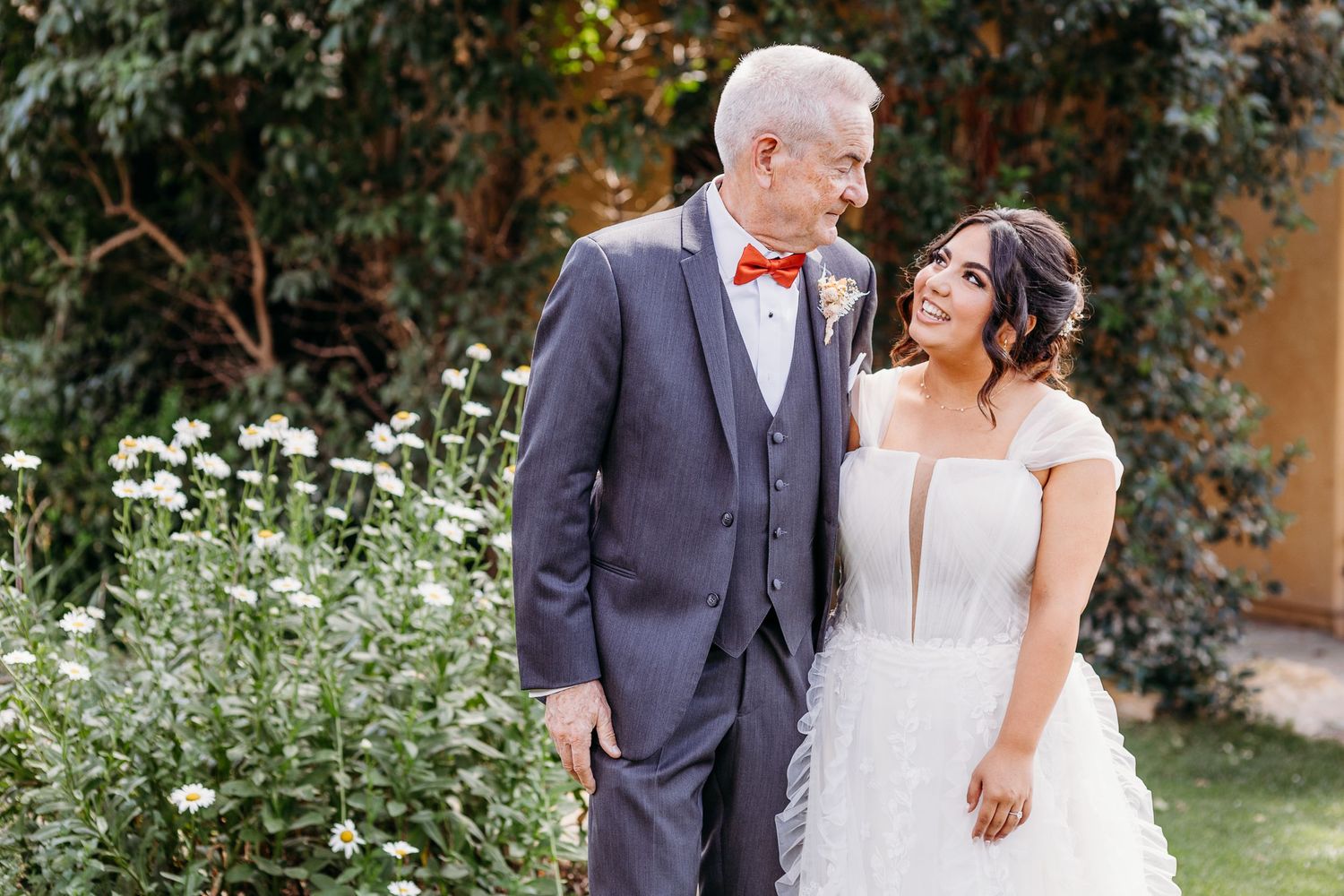 A couple in wedding attire standing together in a garden setting.