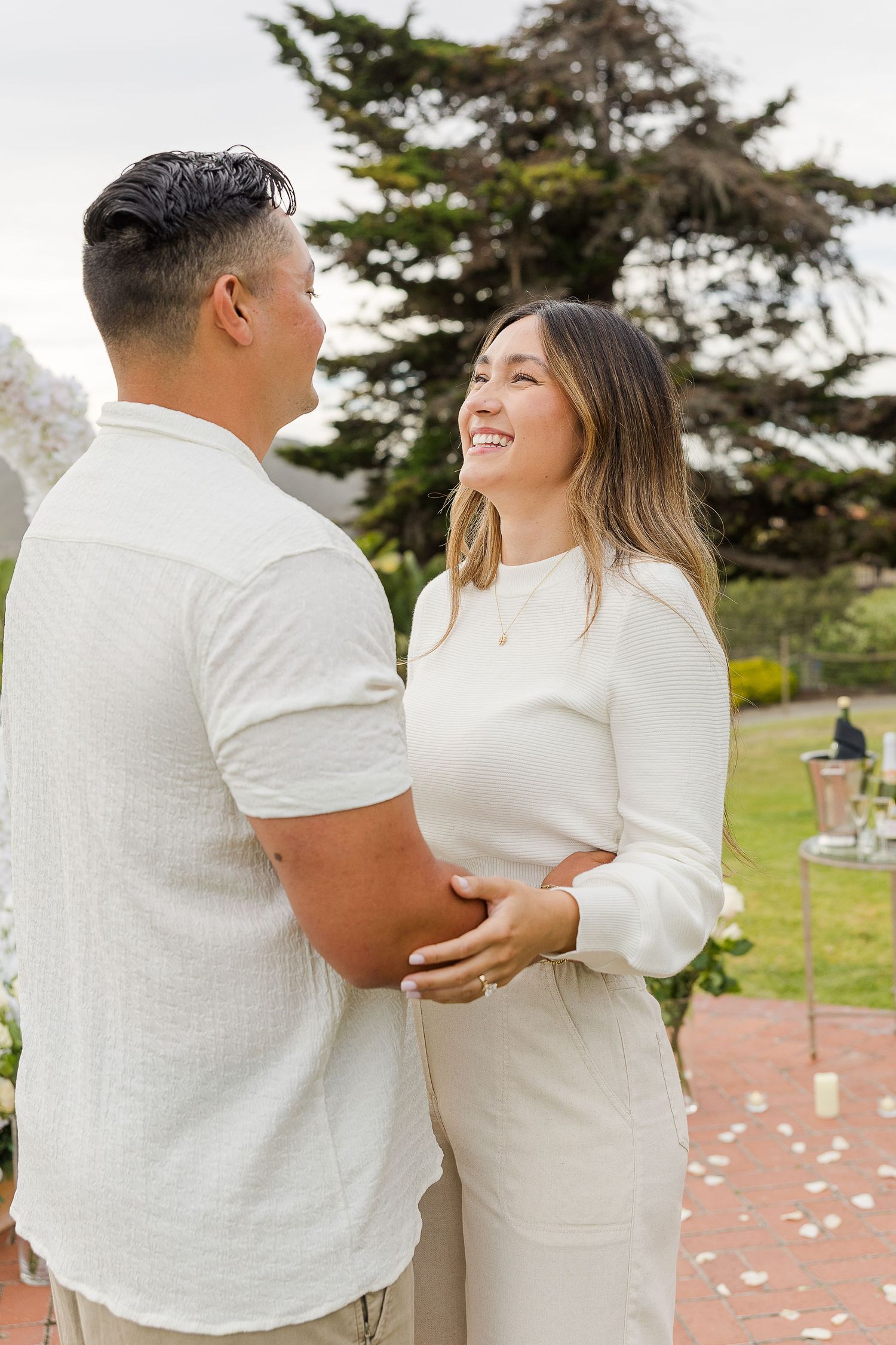 A joyful couple in matching white outfits sharing a romantic moment while dancing outdoors.