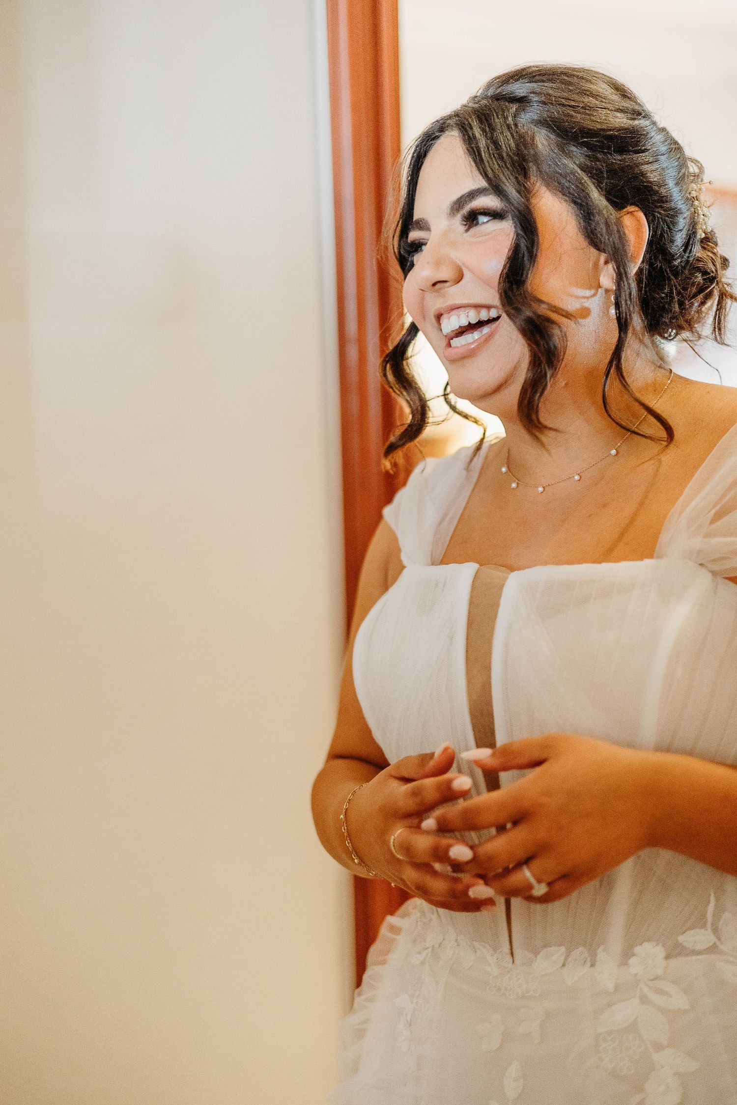 A radiant candid portrait showcasing natural joy and elegant bridal details against warm wooden tones.