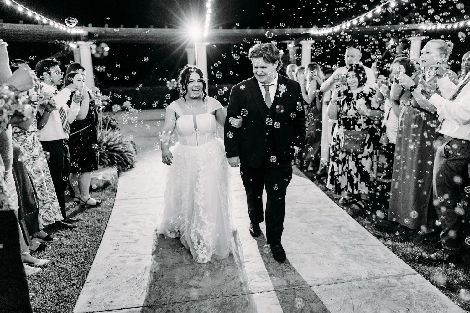 Wedding guests line pathway creating magical exit with sparklers for the newlyweds.