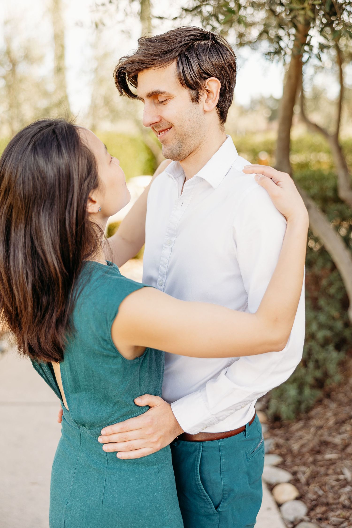 A tender moment between a couple in coordinated outfits of white and teal.