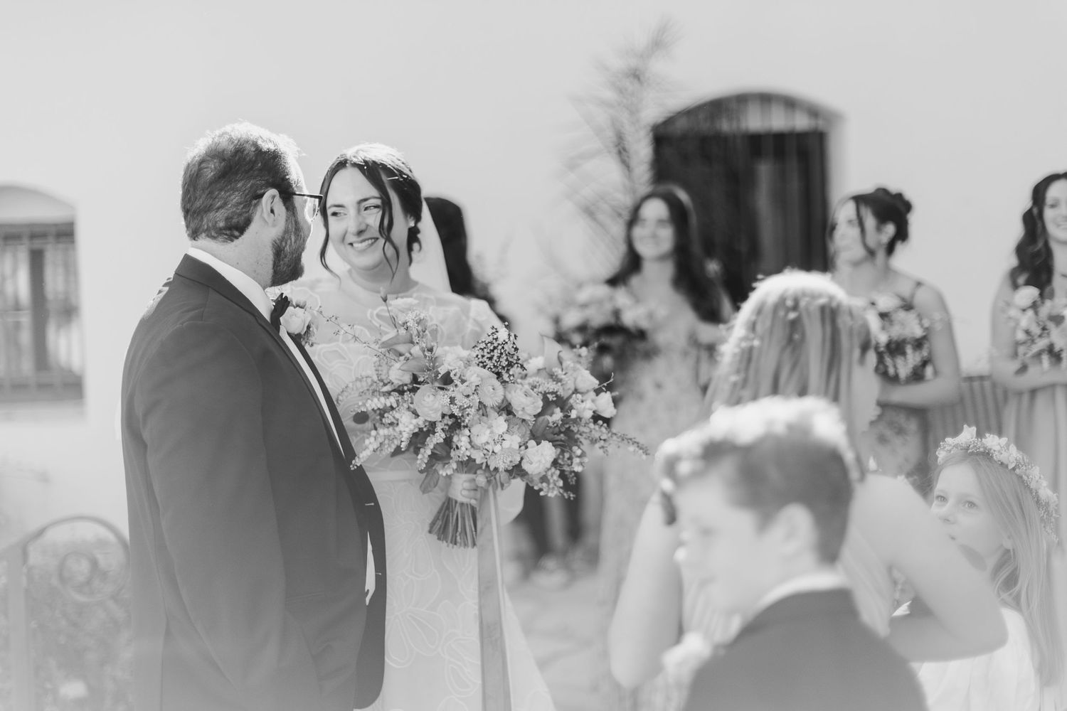 Black and white outdoor wedding ceremony photo with bouquet outside SLO mission.